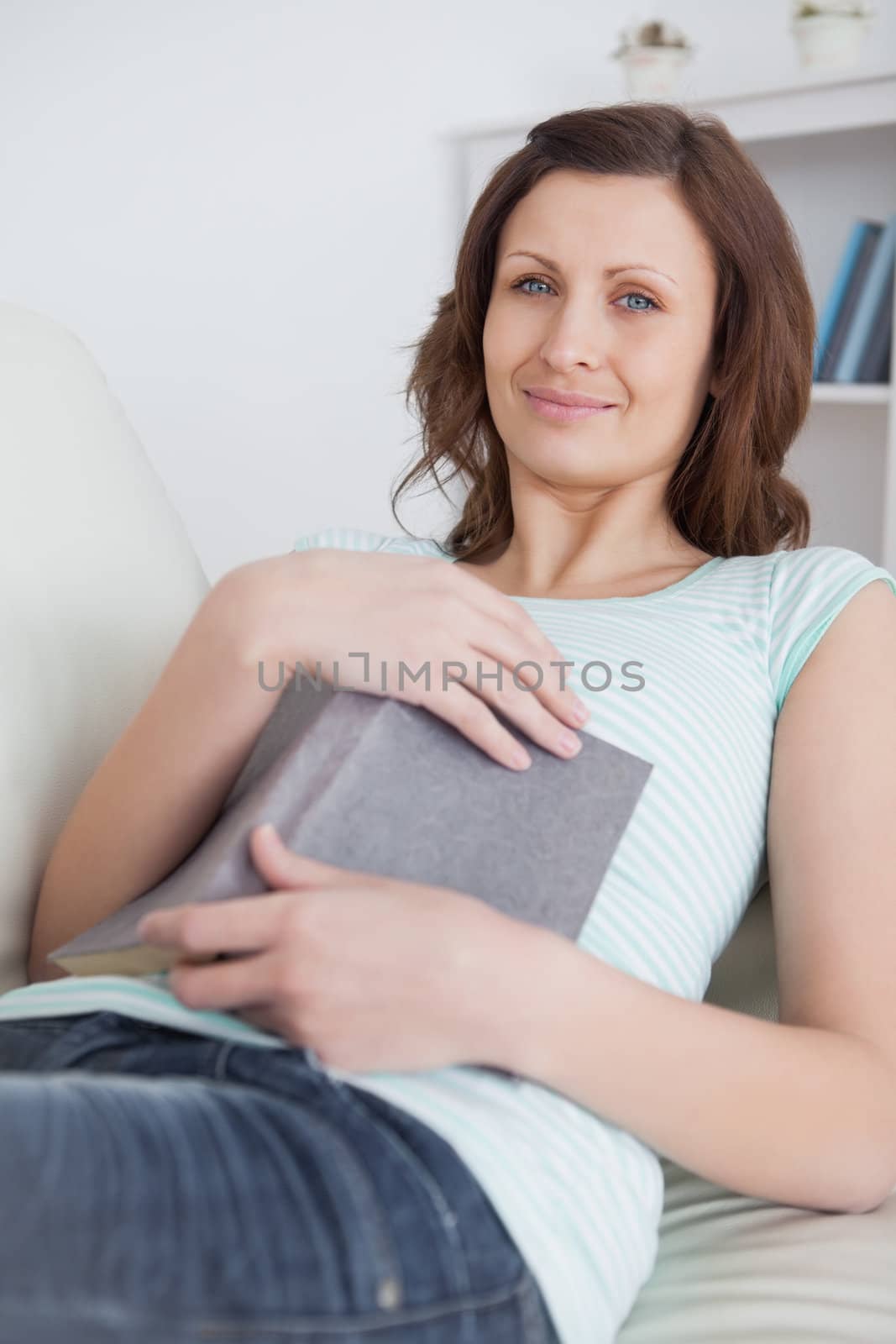 Woman putting a book on her belly in a living room