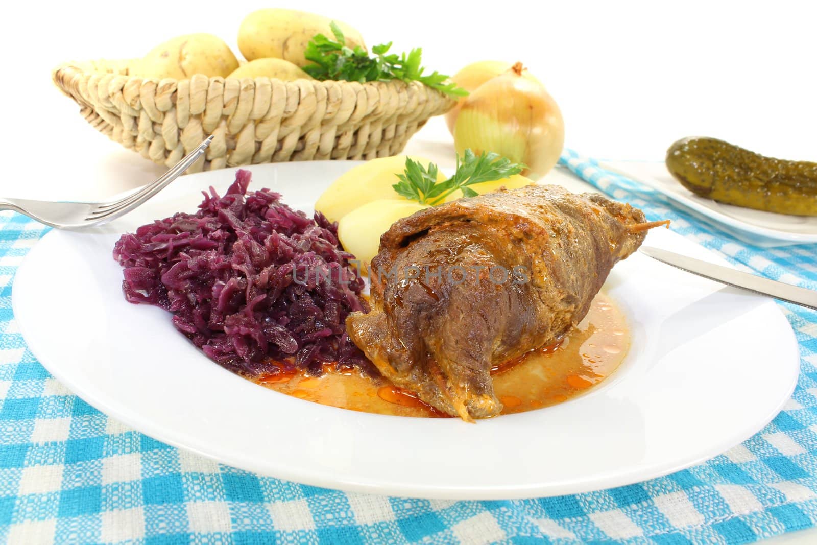 fresh roasted beef roulade with potatoes and red cabbage on a bright background