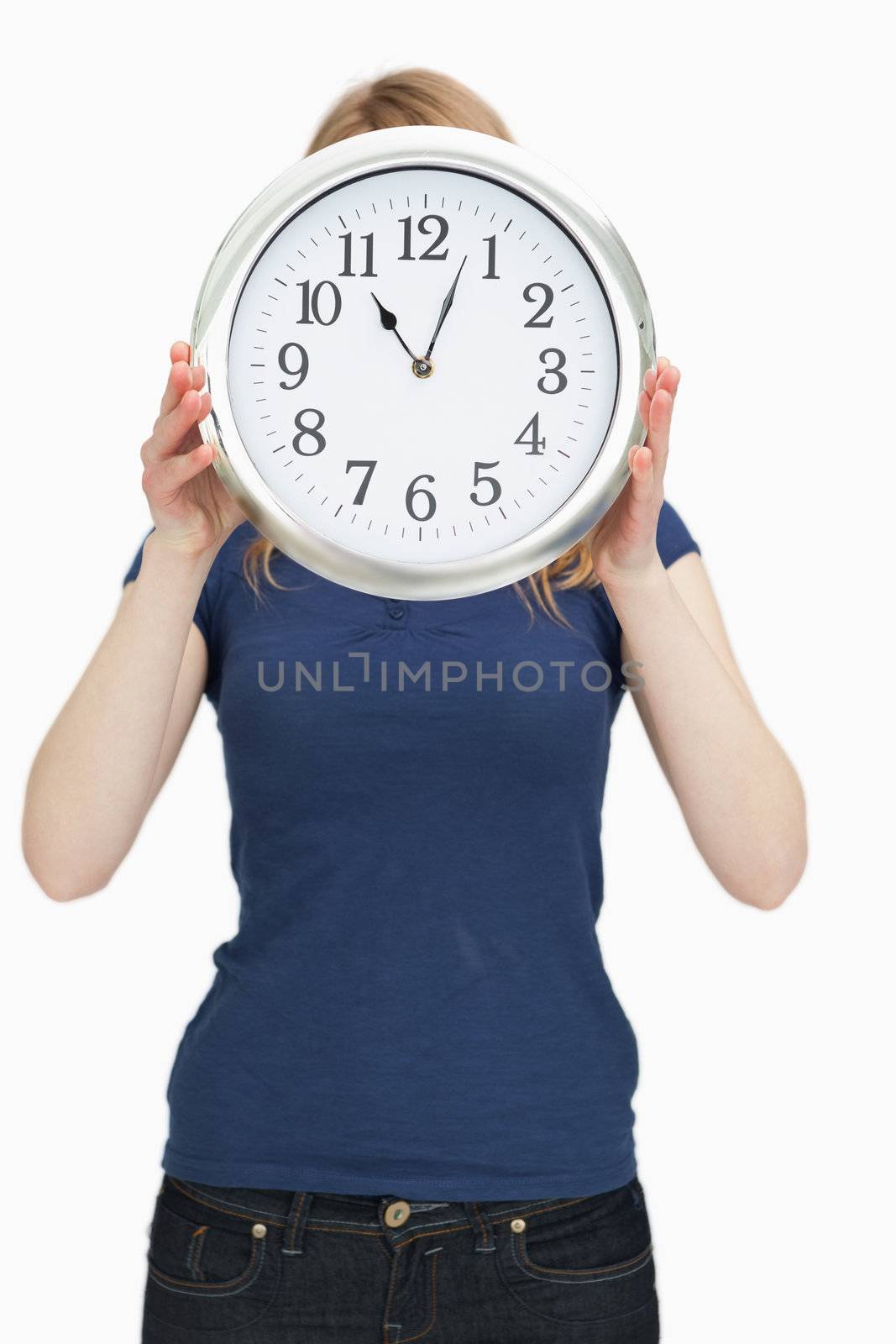 Woman holding a clock in front of her face against a white background