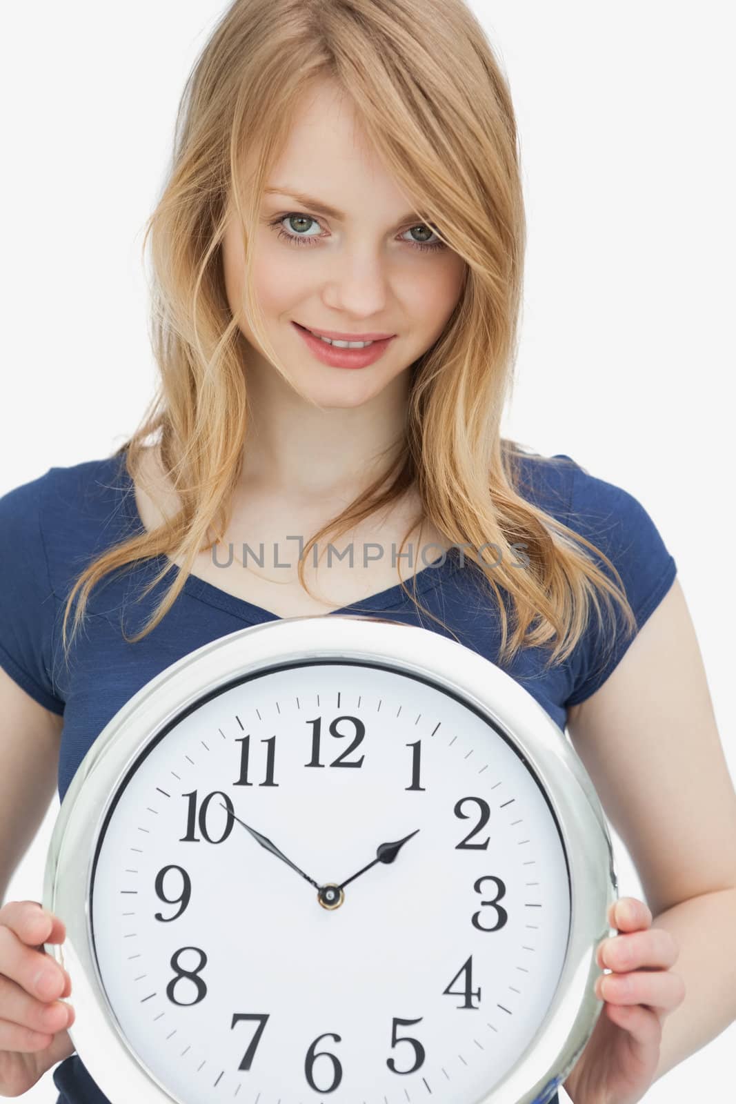Woman holding a clock while looking at camera against a white background