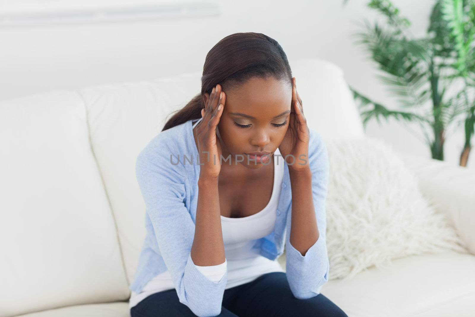 Black woman holding her head in a living room
