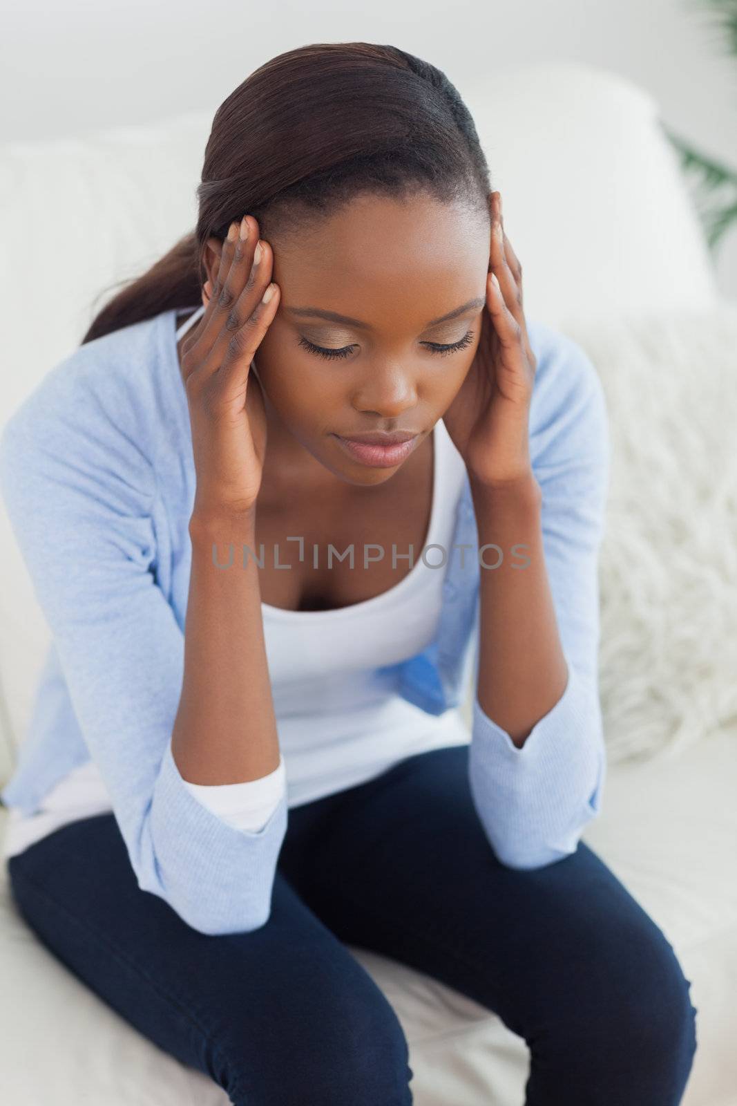 Close up of a black woman holding her head in a living room