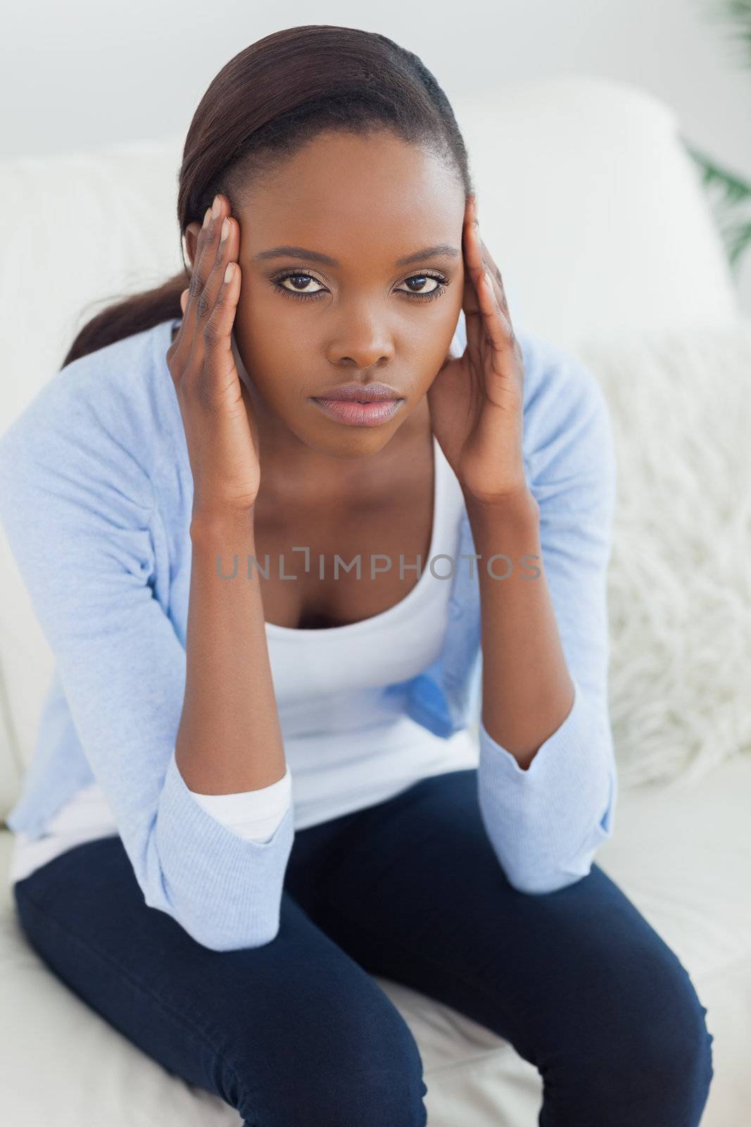 Black woman putting hands on temples in a living room