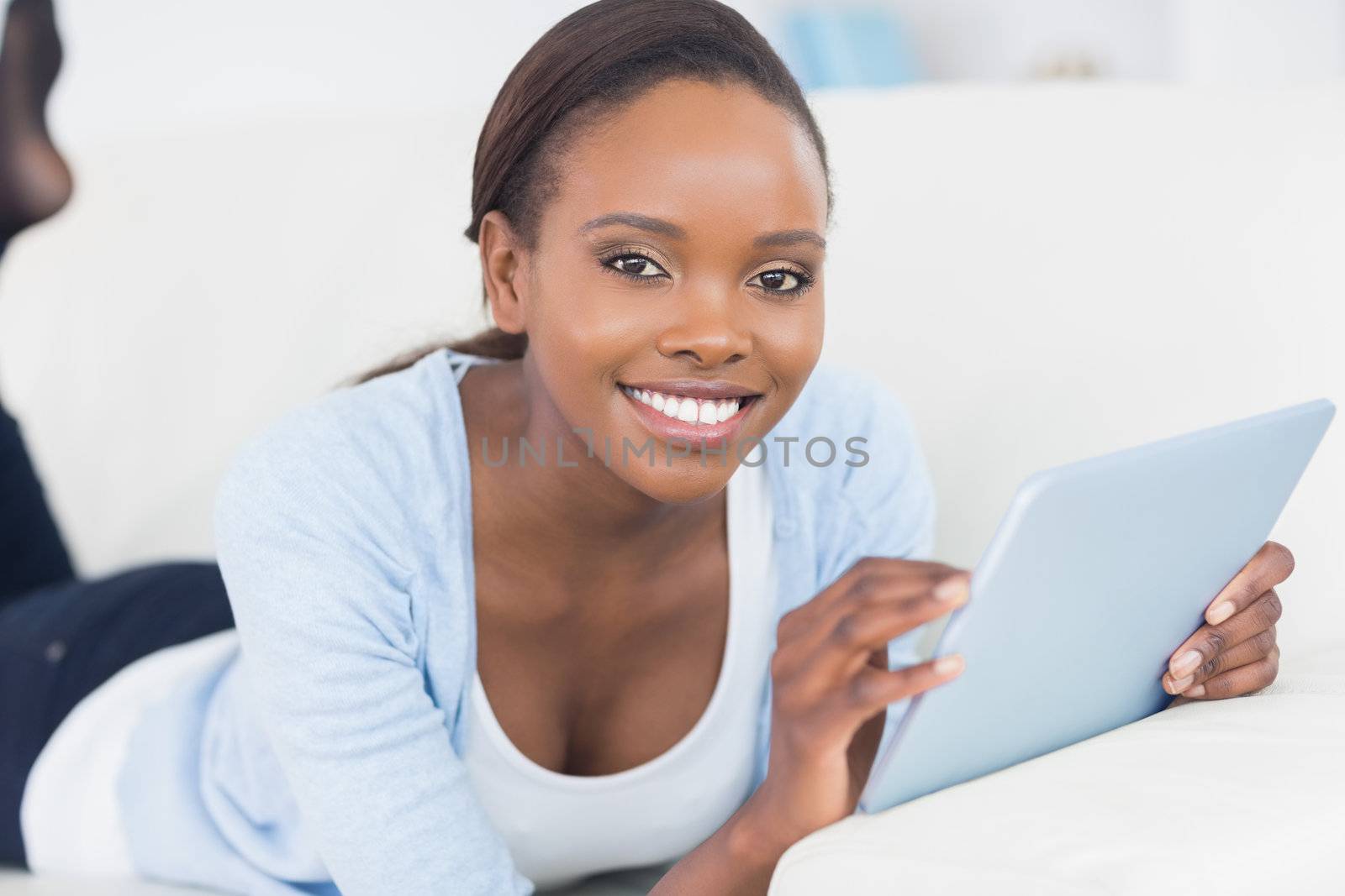 Black woman smiling while holding a tablet computer in a living room
