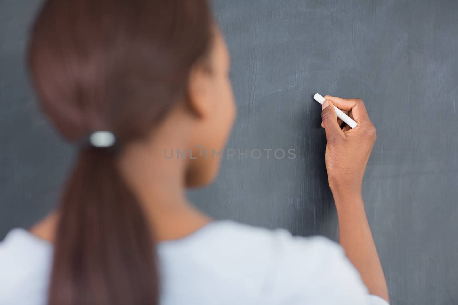 Focus on a black woman writing on a blackboard in a classroom