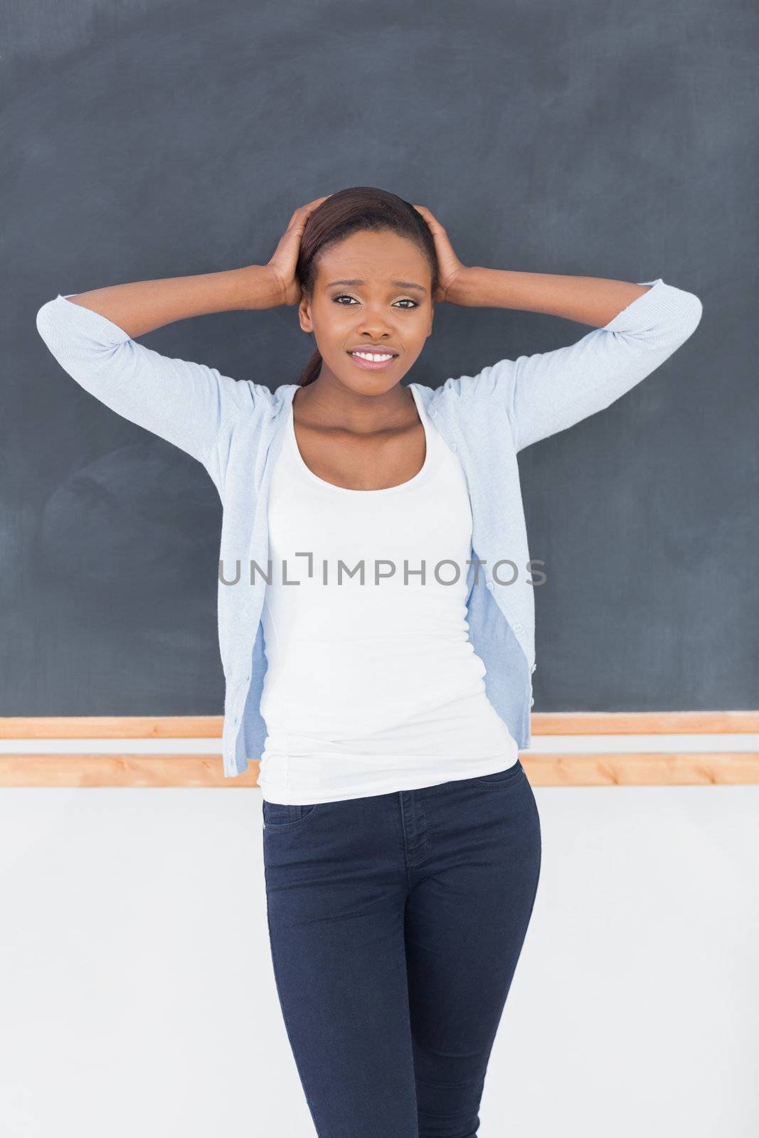 Black woman upset next to a blackboard in a classroom