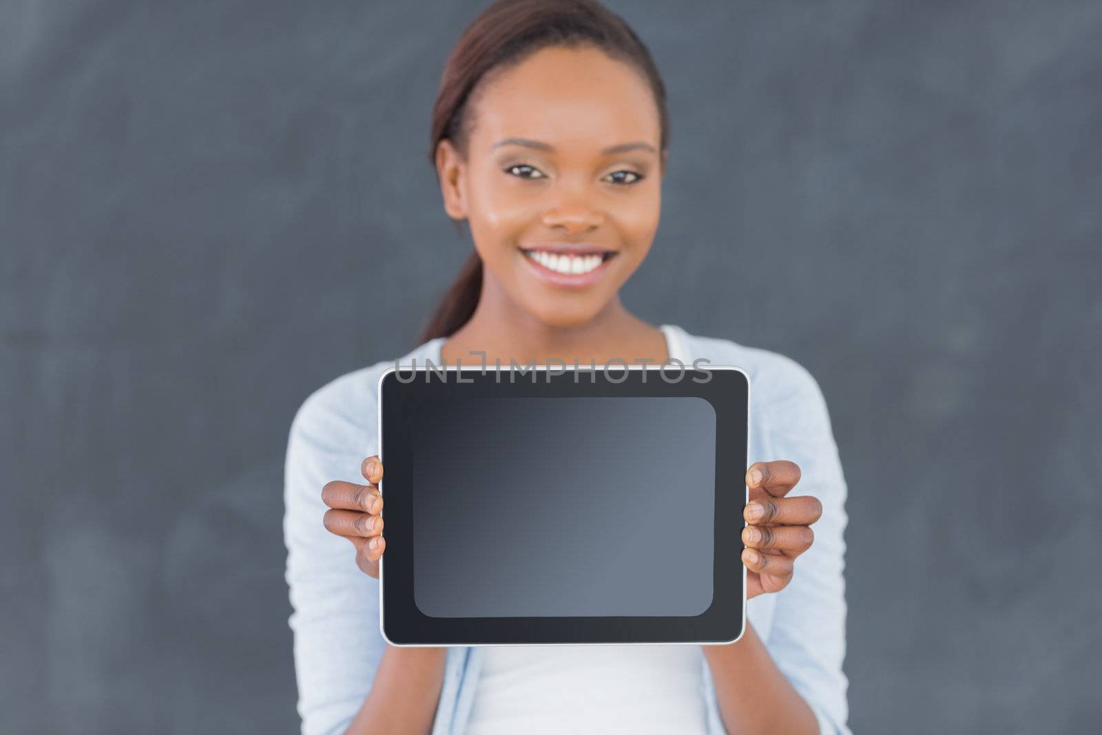 Black woman holding a tablet computer next to a blackboard in a classroom