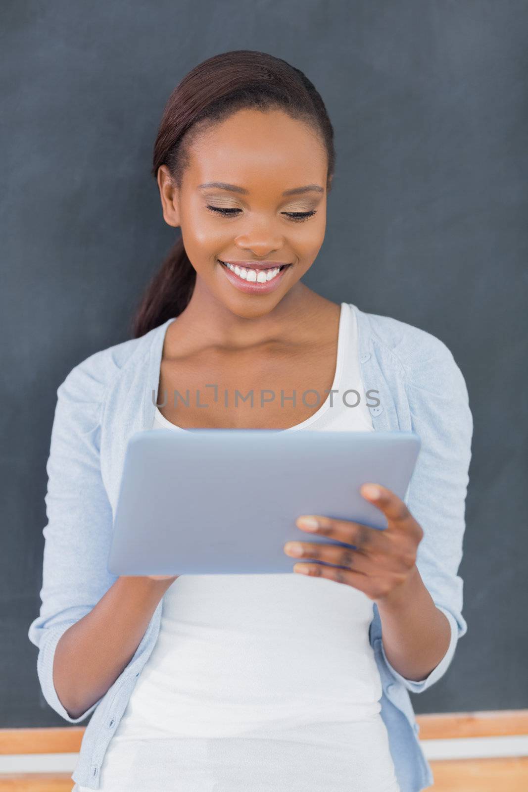 Front view of a black woman looking at a tablet computer in a classroom