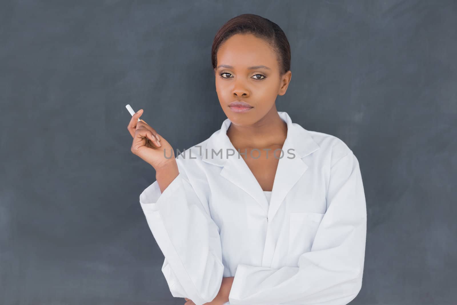 Teacher holding a chalk while looking at camera in a classroom