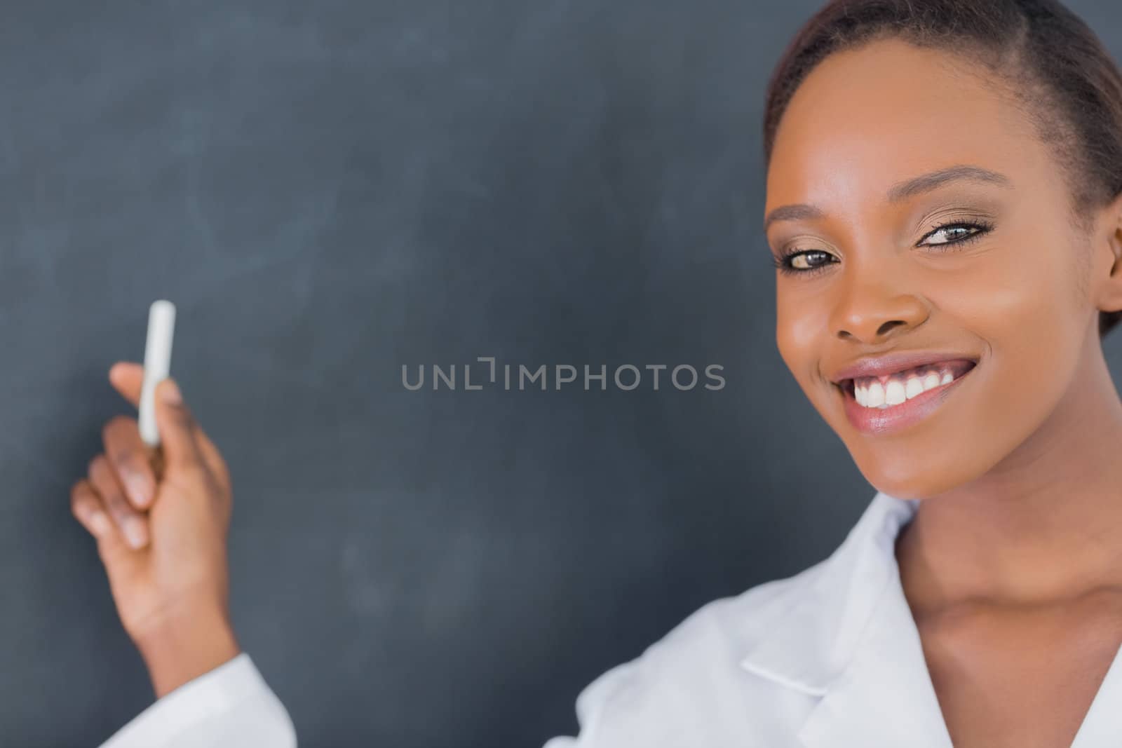 Teacher smiling while holding a chalk in a classroom