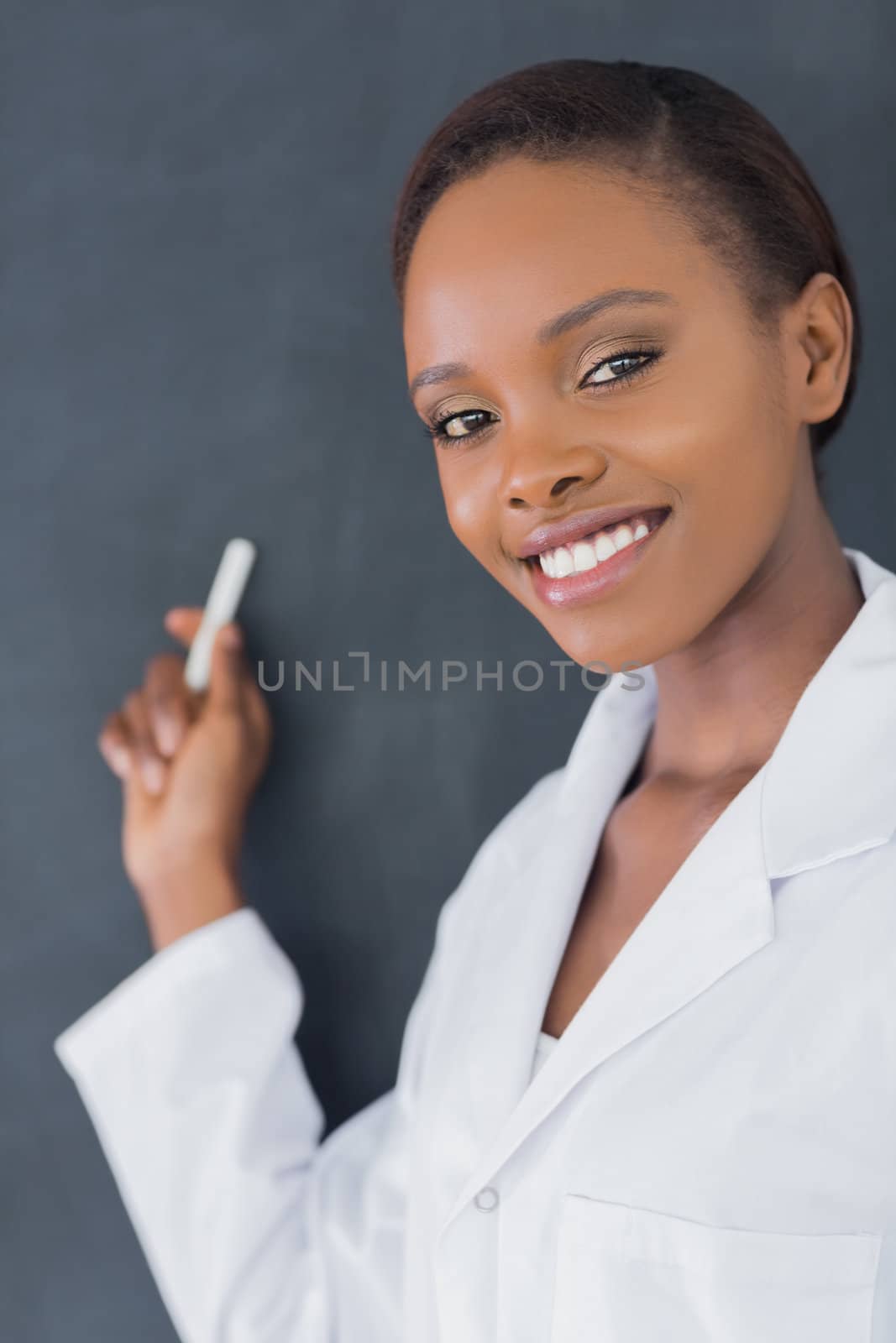 Close up of a teacher smiling while holding a chalk in a classroom