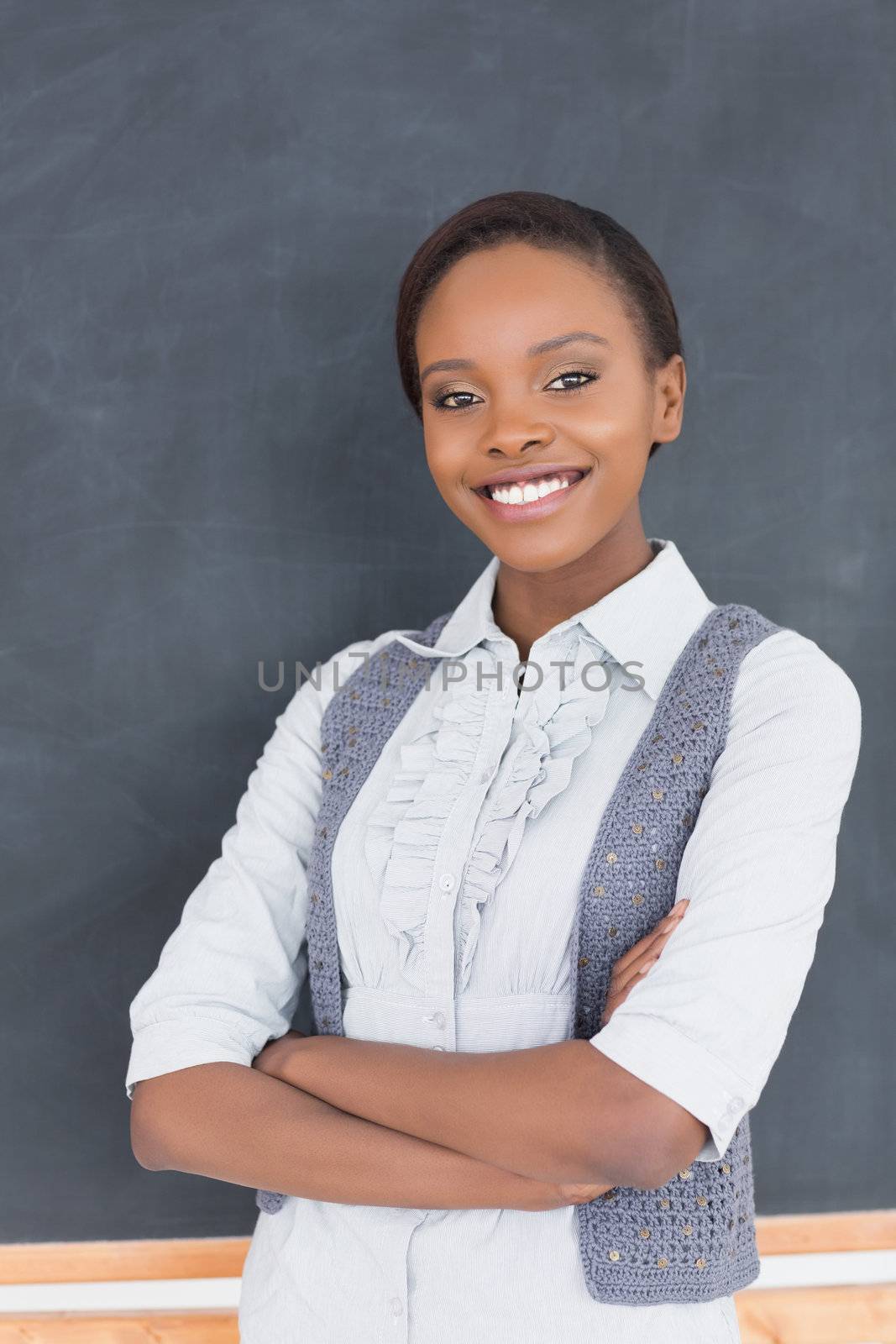 Teacher smiling next to a blackboard in a classroom