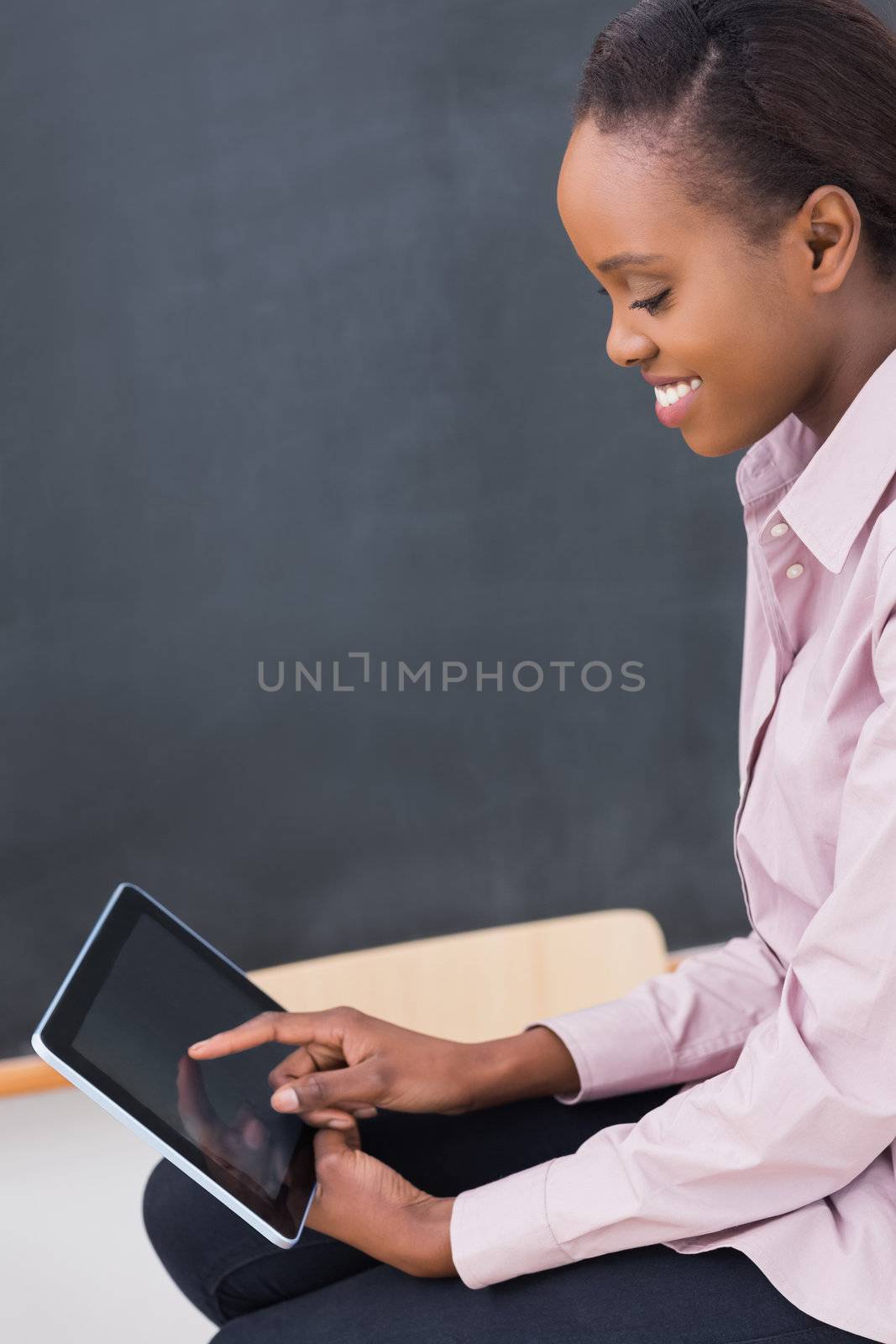 Teacher touching a tablet computer while looking it in a classroom