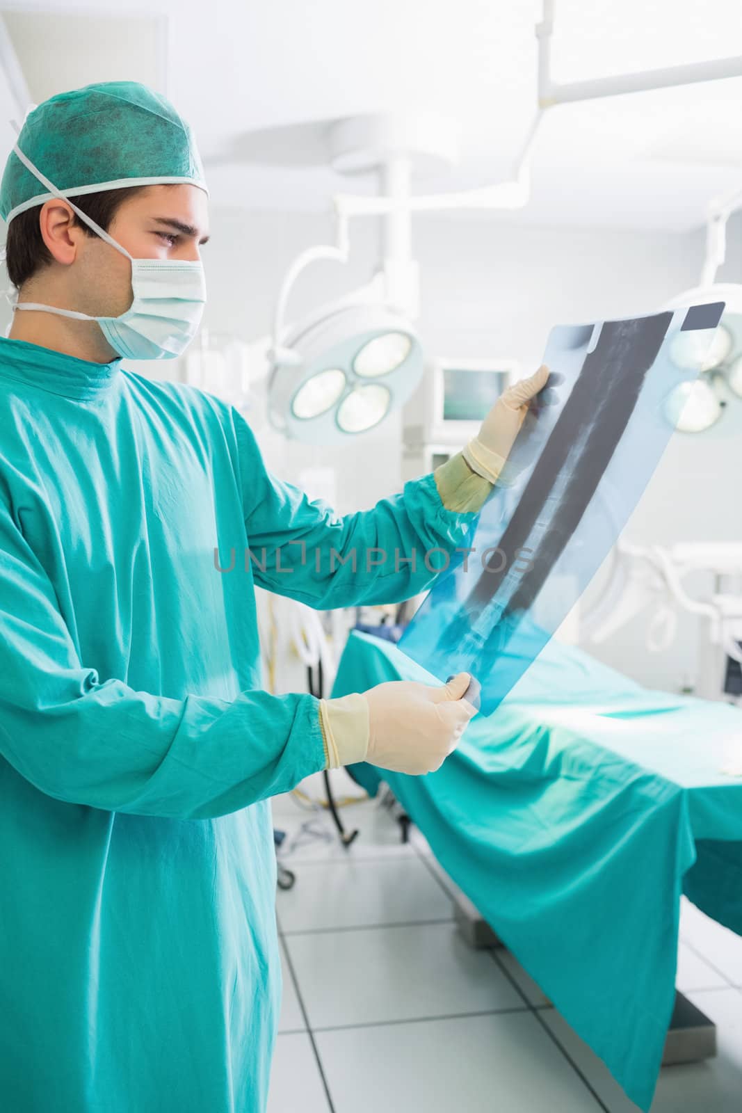Surgeon holding a X-ray while looking at it in an operating theatre