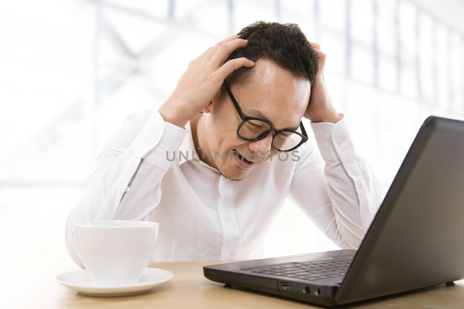 Depressed mid adult Asian business man scratching his head at office