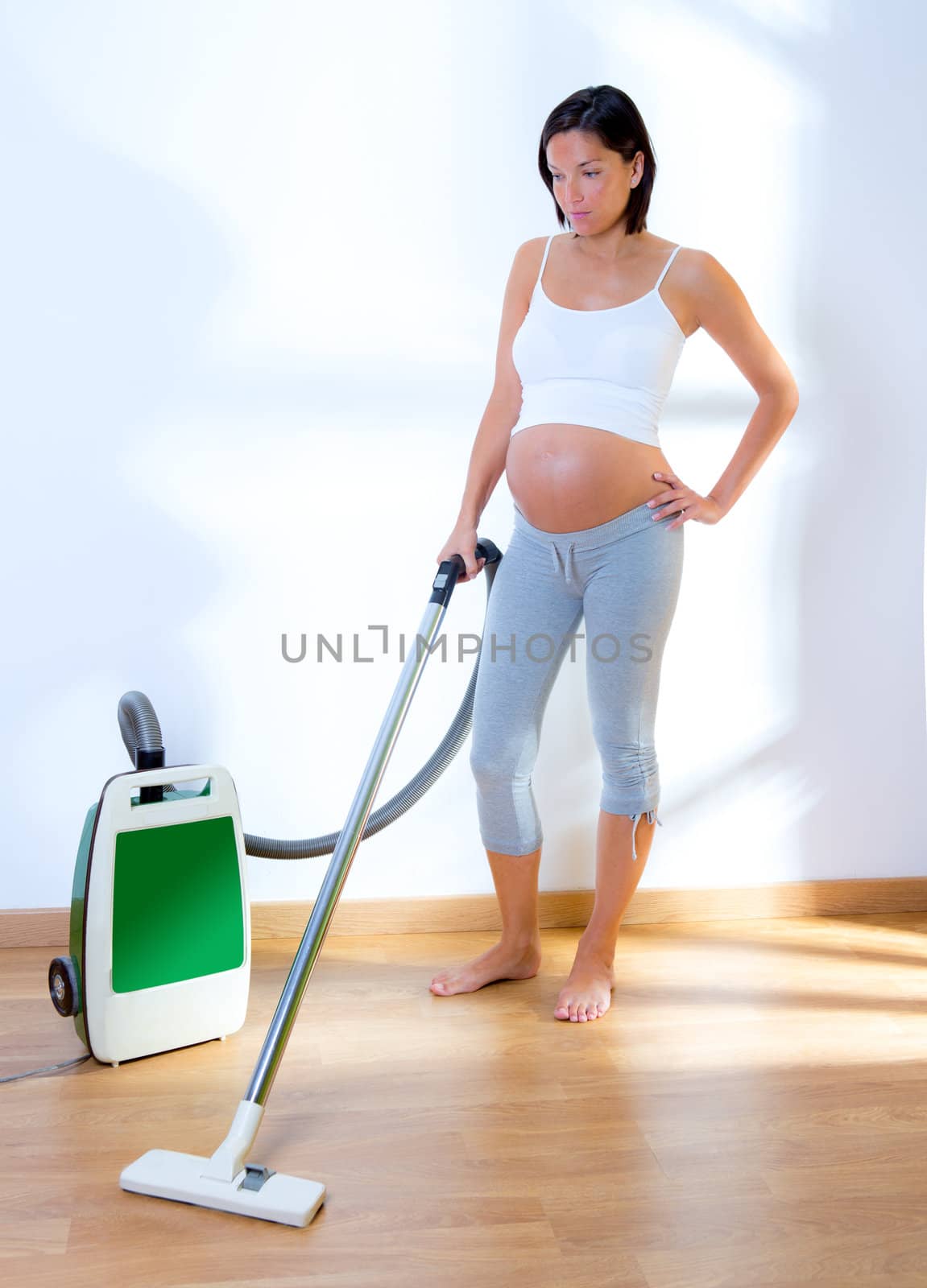 Beautiful pregnant woman retro vacuum cleaner housewife on chores at home