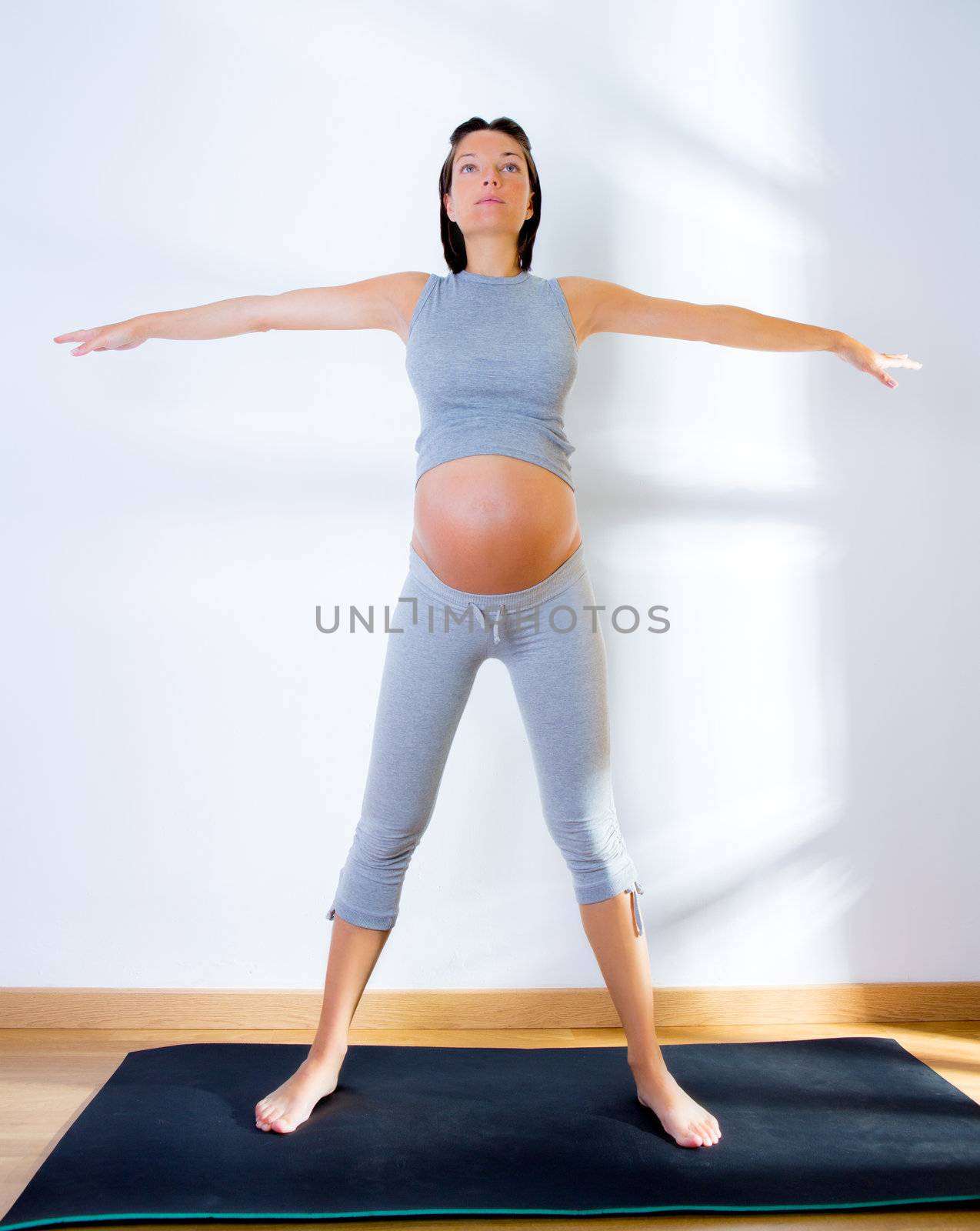 Beautiful pregnant woman at gym fitness exercise practicing aerobics on mat