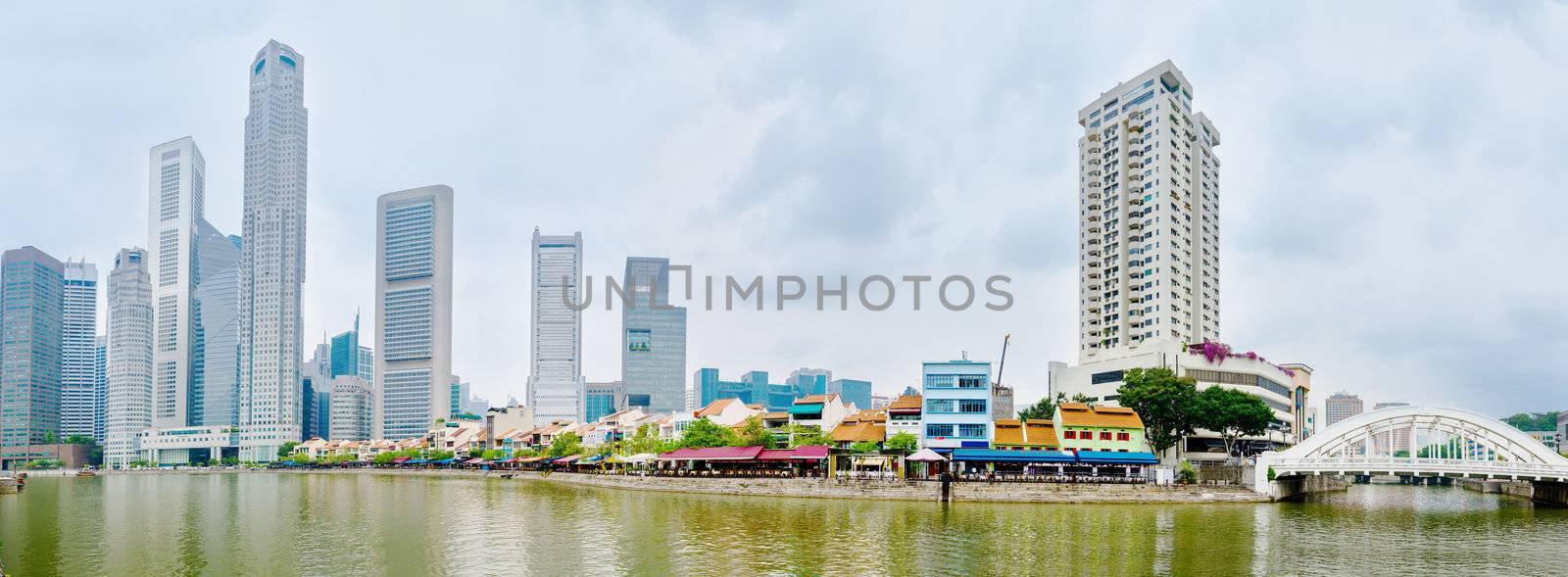 Singapore  river quay with tall skyscrapers in the central business district and and small restaurants on Boat Quay