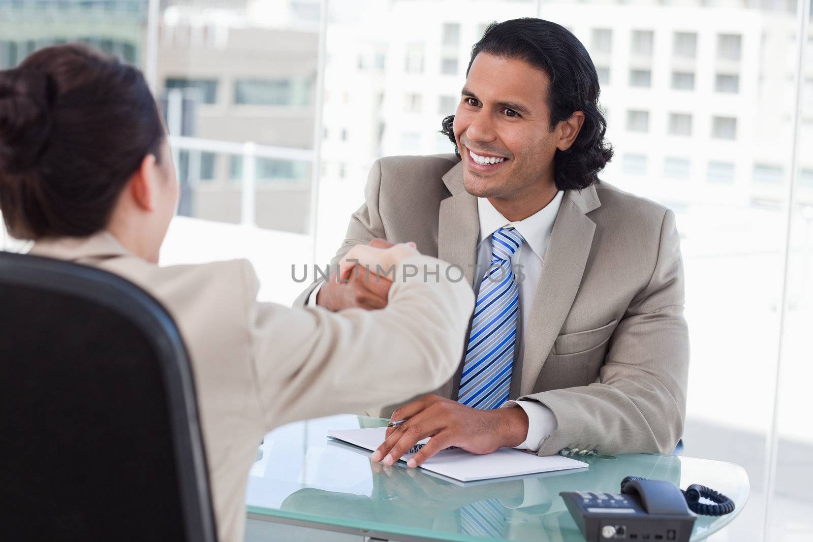 Manager shaking the hand of a female applicant in his office