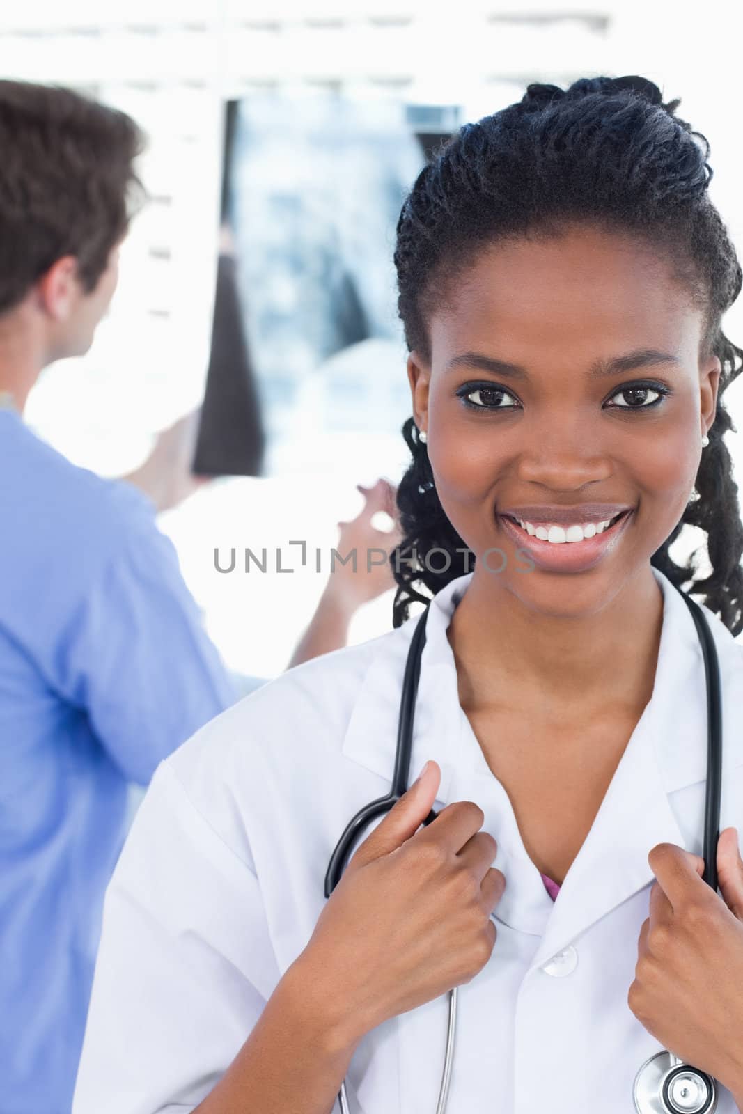 Portrait of a doctor looking at a of X-ray while his colleague is smiling in an office