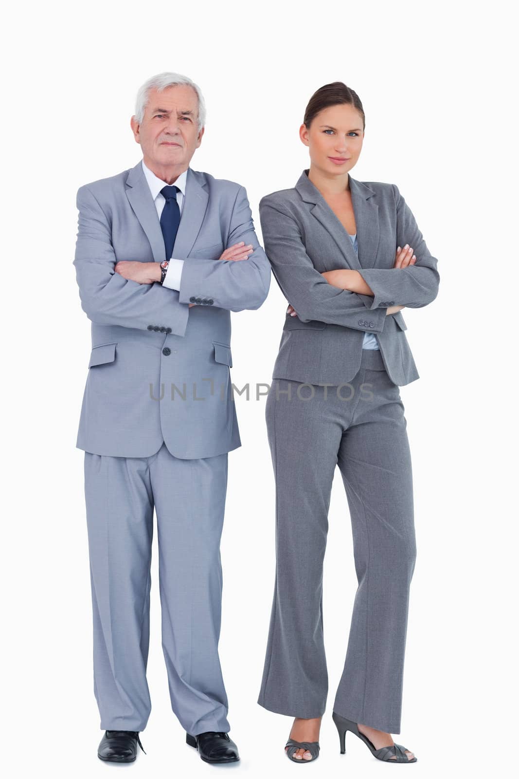 Mature businessman and colleague with arms folded against a white background