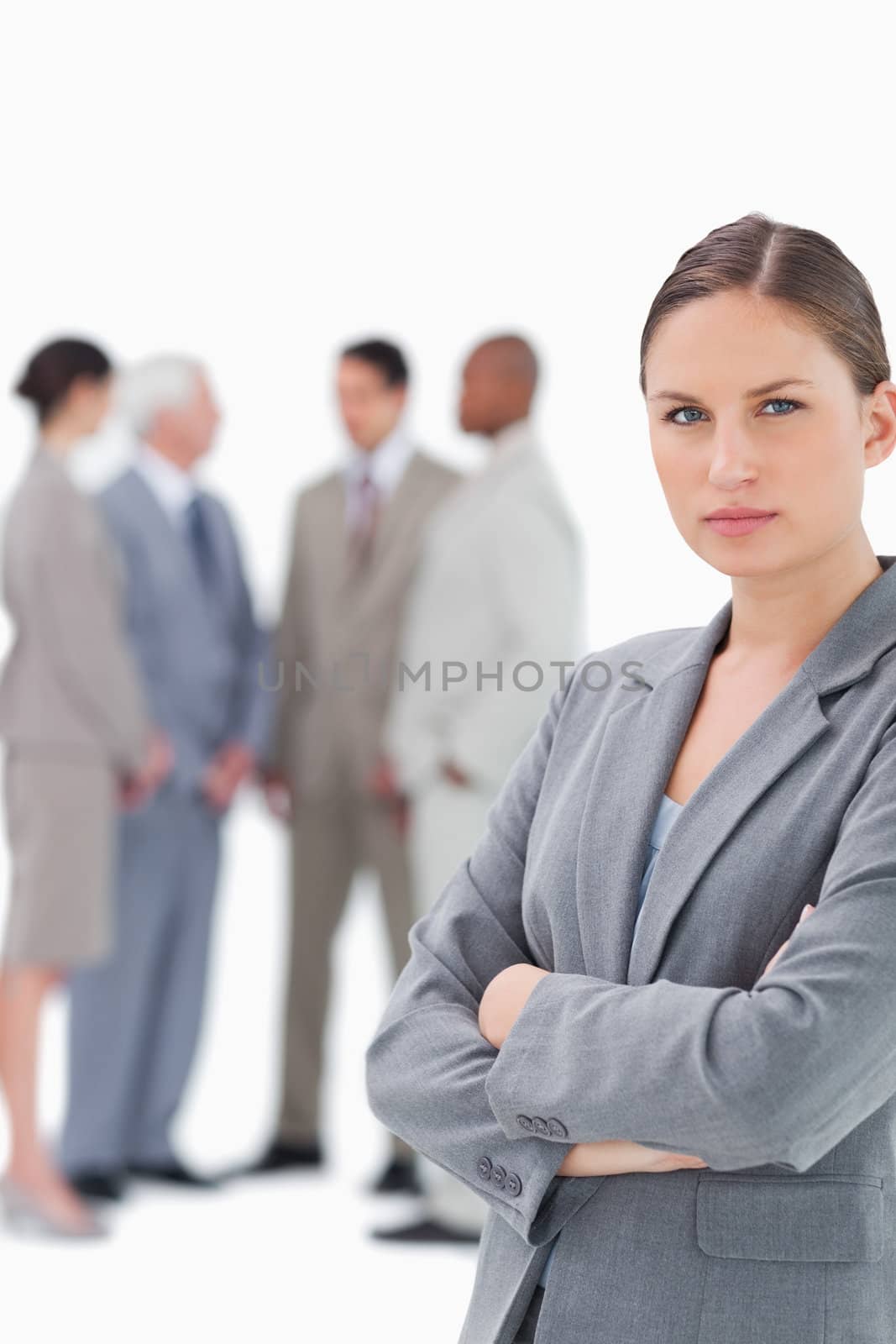 Saleswoman with folded arms and colleagues behind her against a white background