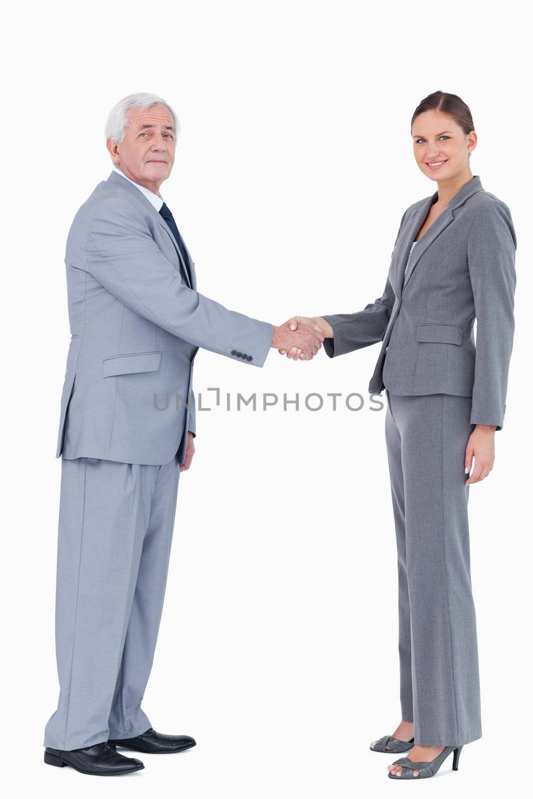 Businessman and woman shaking hands against a white background