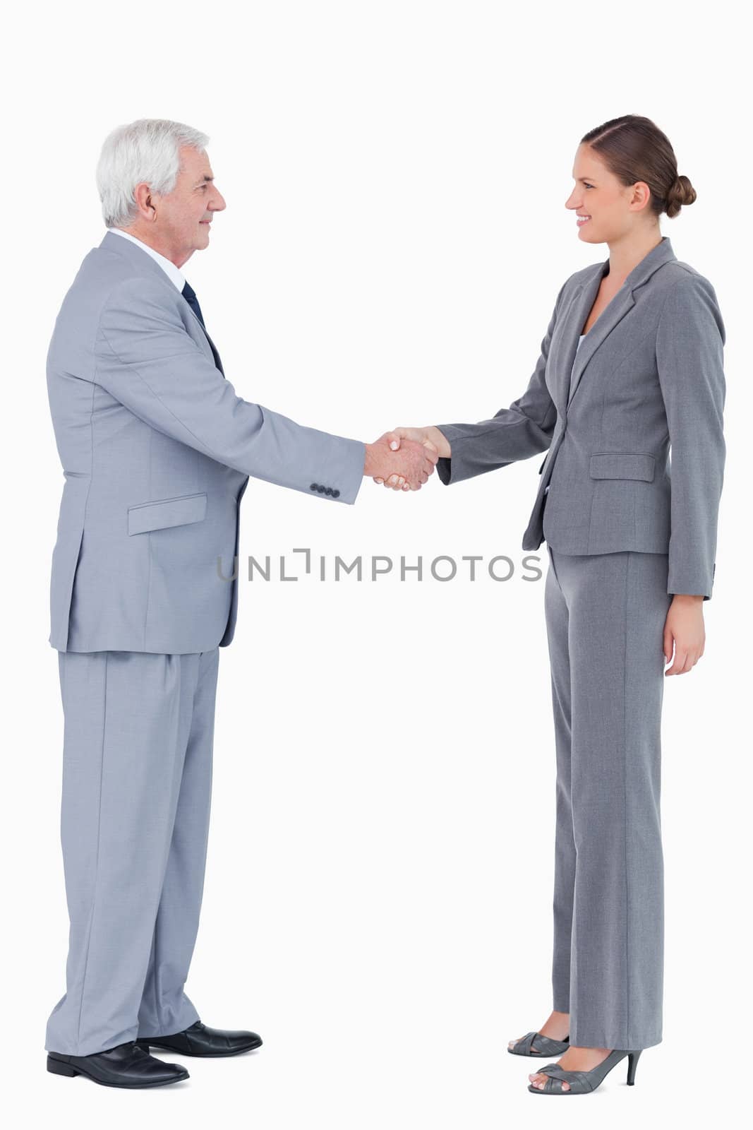 Side view of smiling businesspartner shaking hands against a white background