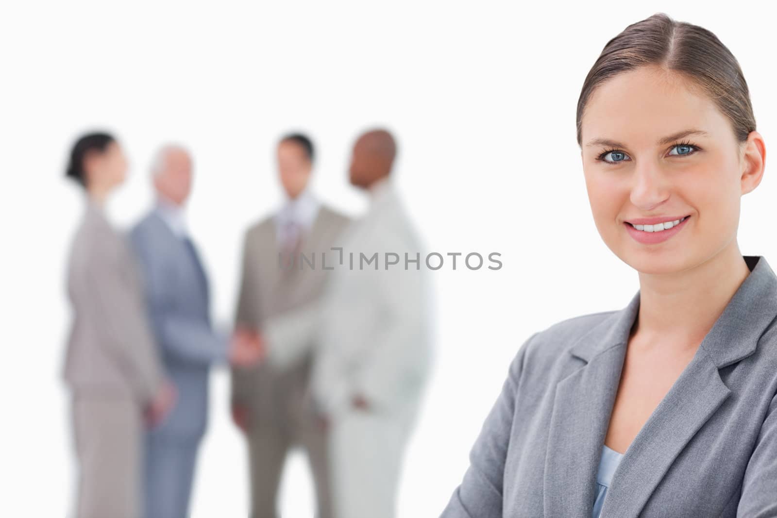 Smiling saleswoman with colleagues behind her against a white background
