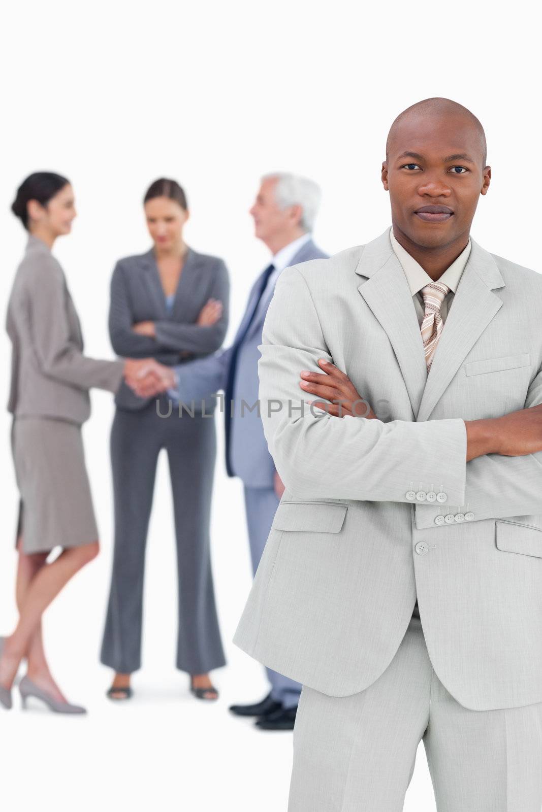 Businessman with folded arms and trading partners behind him against a white background