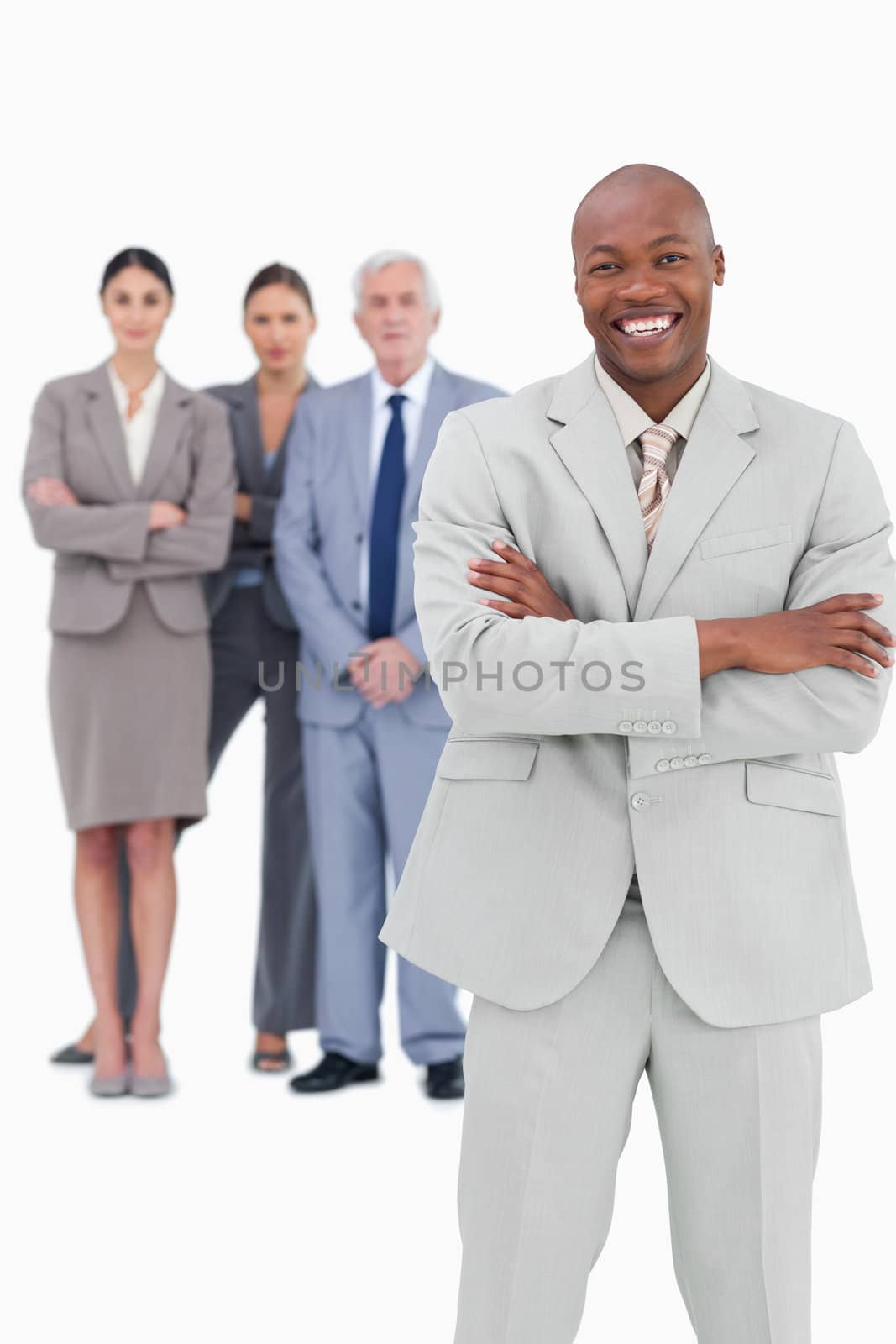 Smiling businessman with arms folded and team behind him against a white background