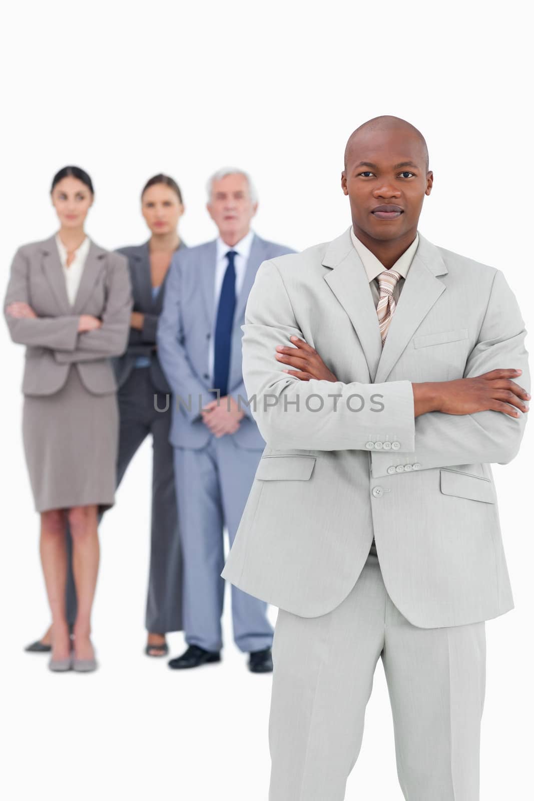 Businessman with folded arms and team behind him against a white background