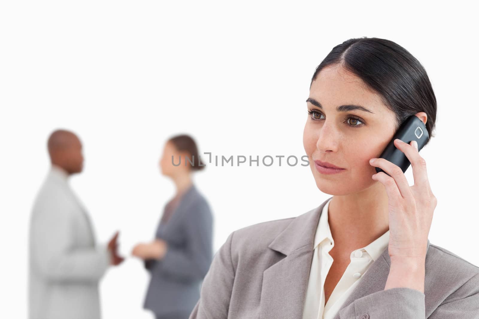 Saleswoman with cellphone and colleagues behind her against a white background