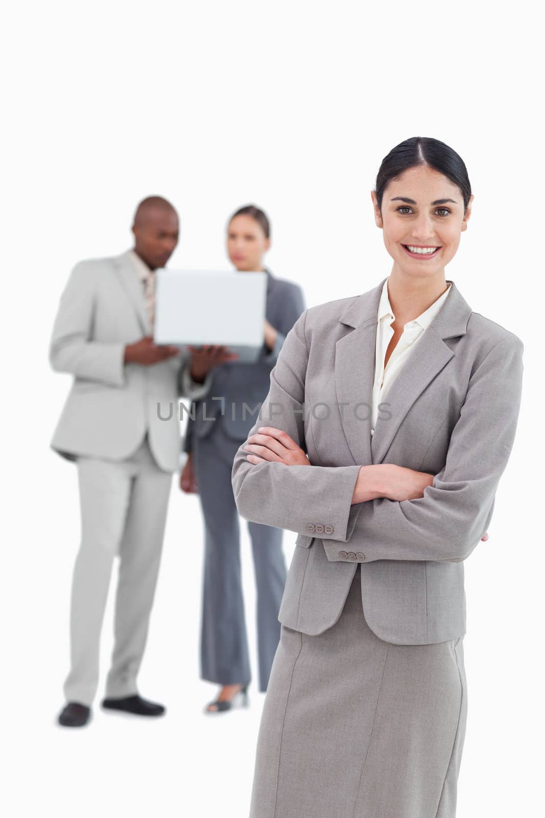 Smiling tradeswoman with folded arms and co-workers behind her against a white background