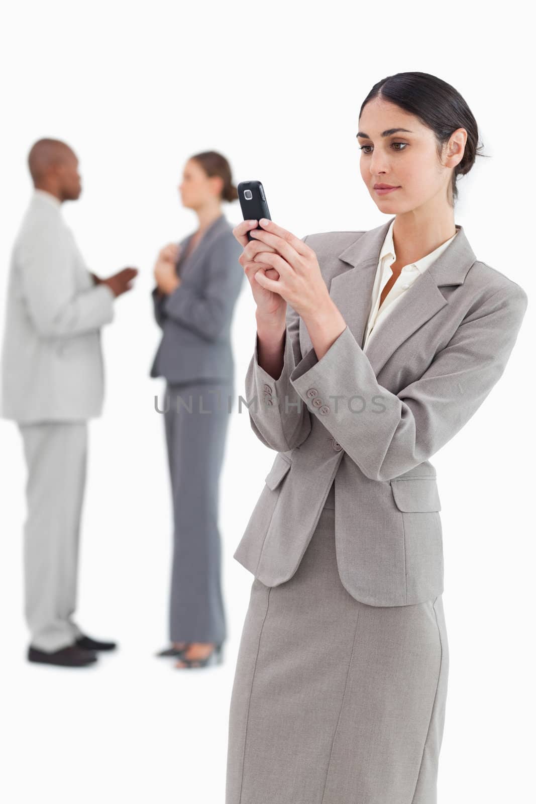 Businesswoman reading text message with colleagues behind by Wavebreakmedia