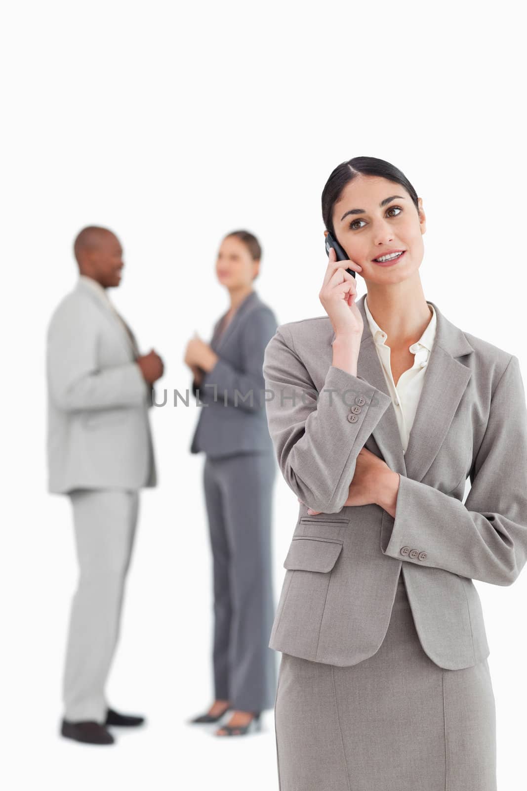 Businesswoman with cellphone and colleagues behind her against a white background