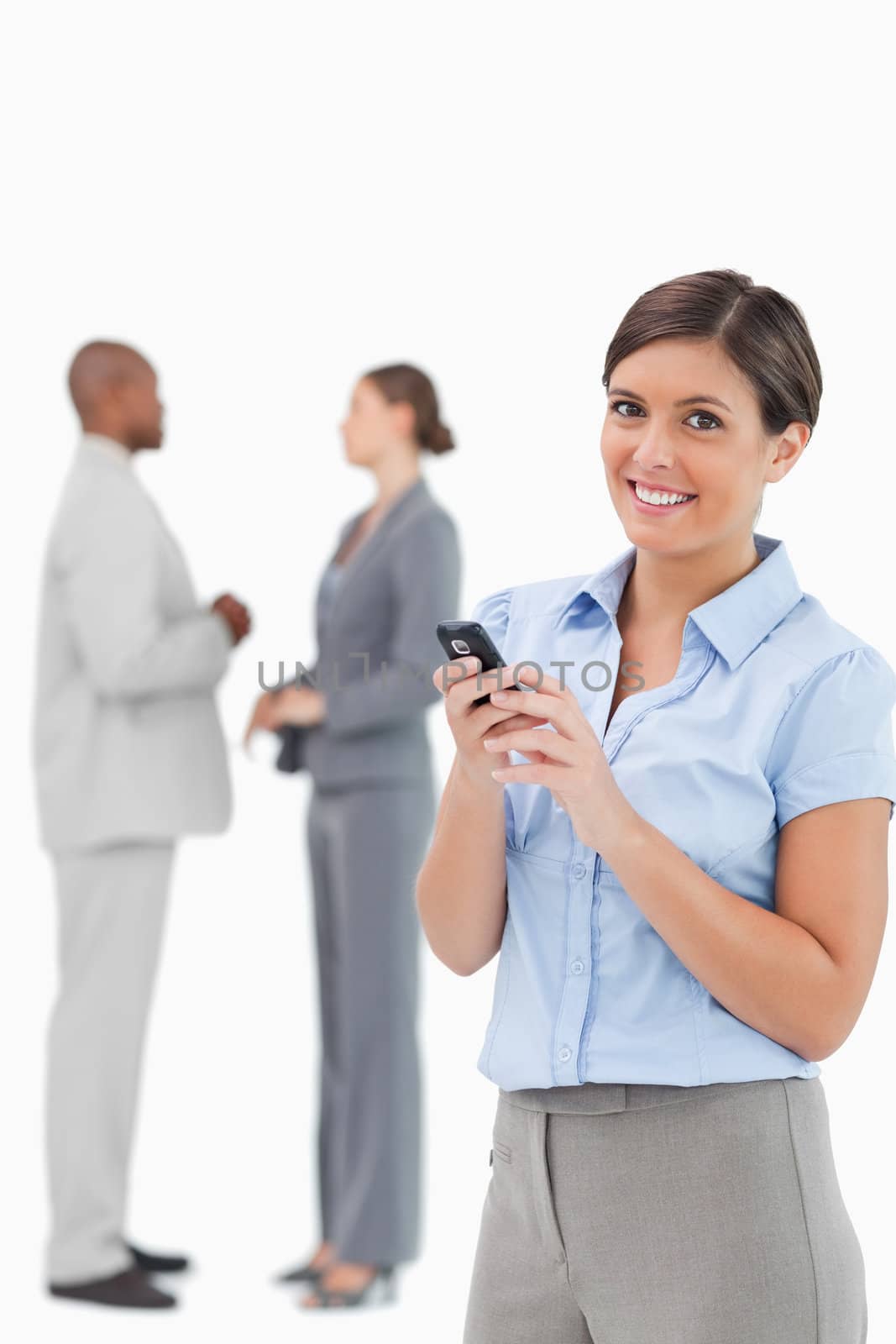 Smiling tradeswoman with cellphone and associates behind her against a white background