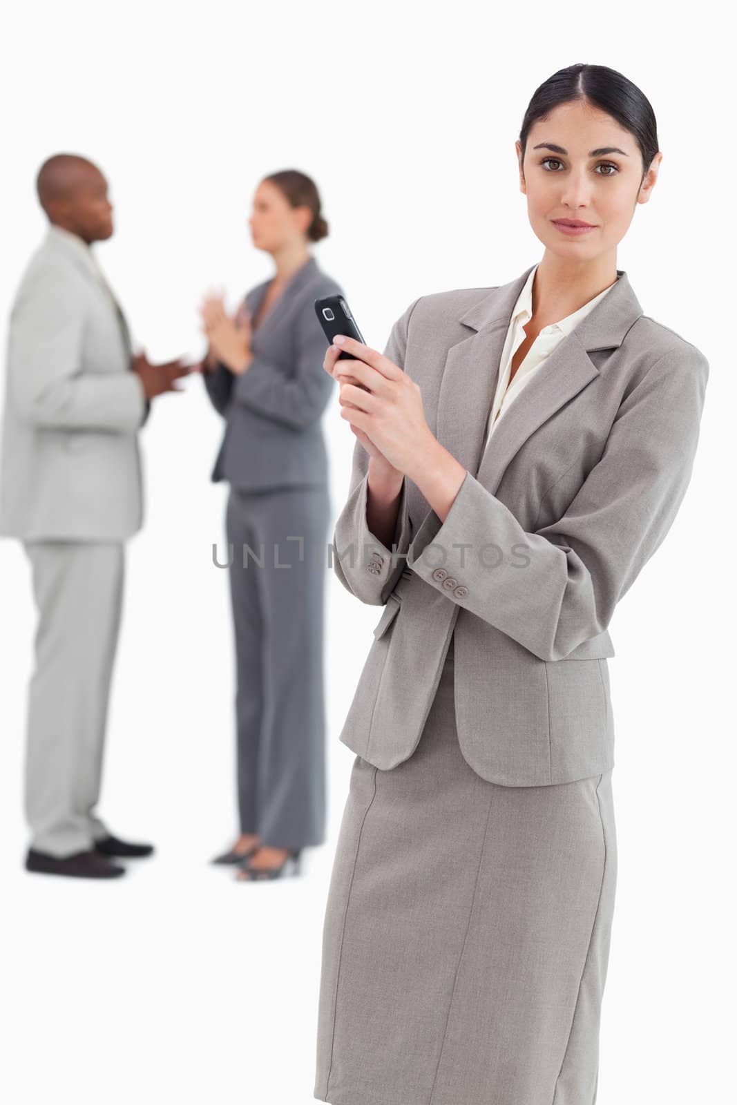 Saleswoman holding cellphone and colleagues behind her against a white background