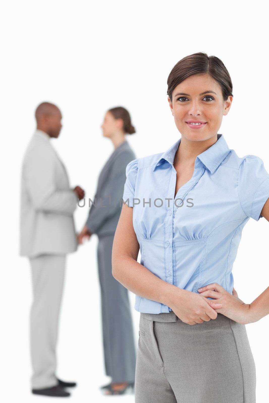 Smiling tradeswoman with talking colleagues behind her against a white background