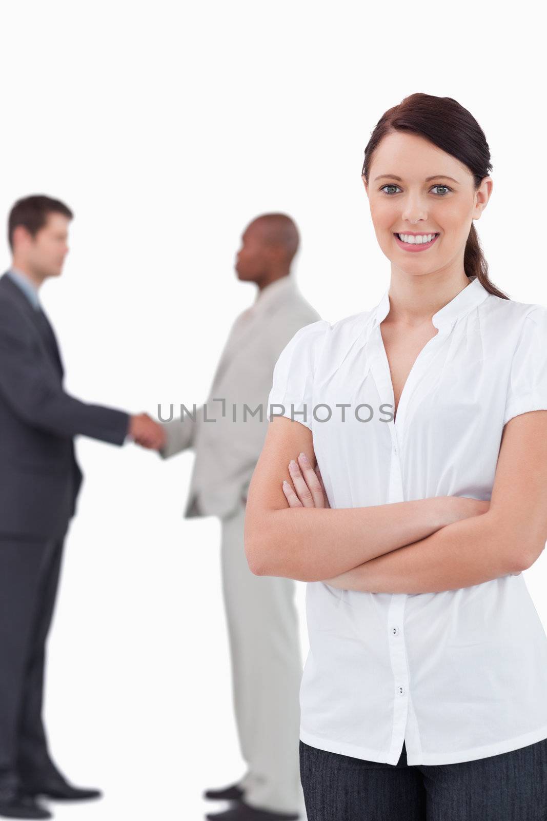 Tradeswoman with arms folded and hand shaking trading partners behind her against a white background