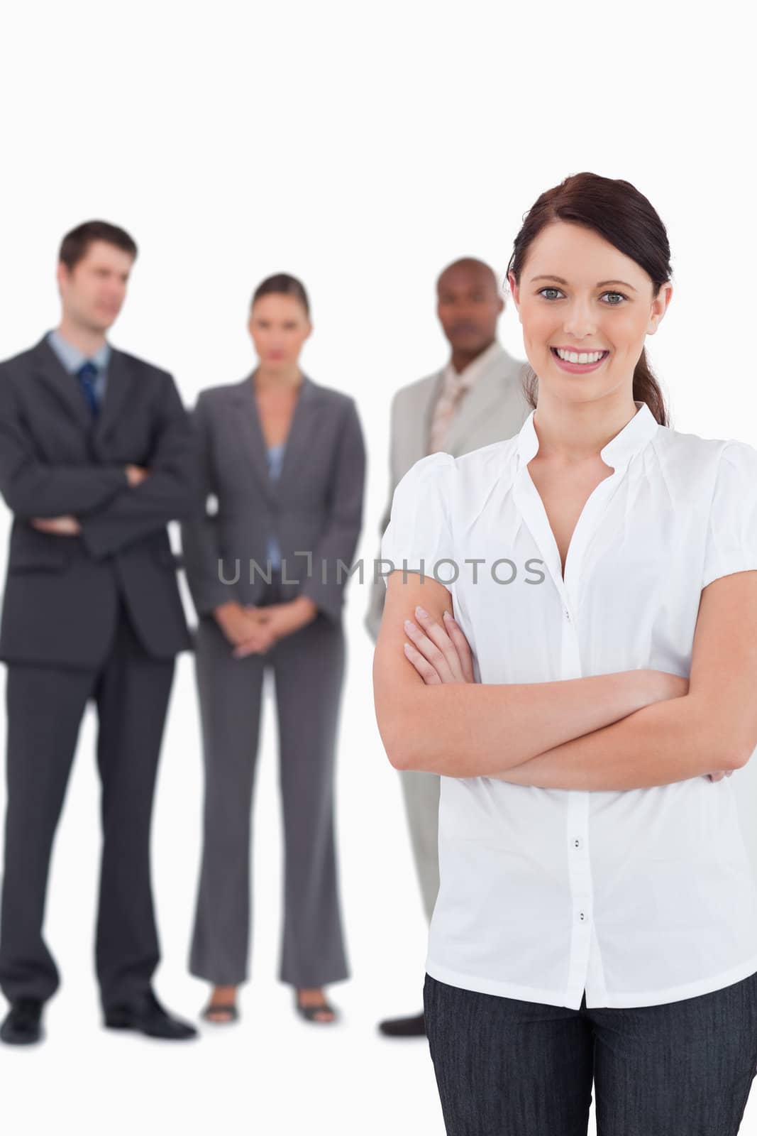 Businesswoman with arms folded and three colleagues behind her against a white background