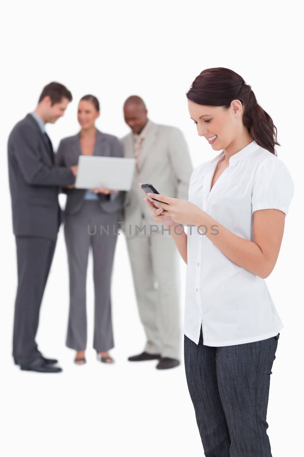 Saleswoman with mobile phone and colleagues behind her against a white background