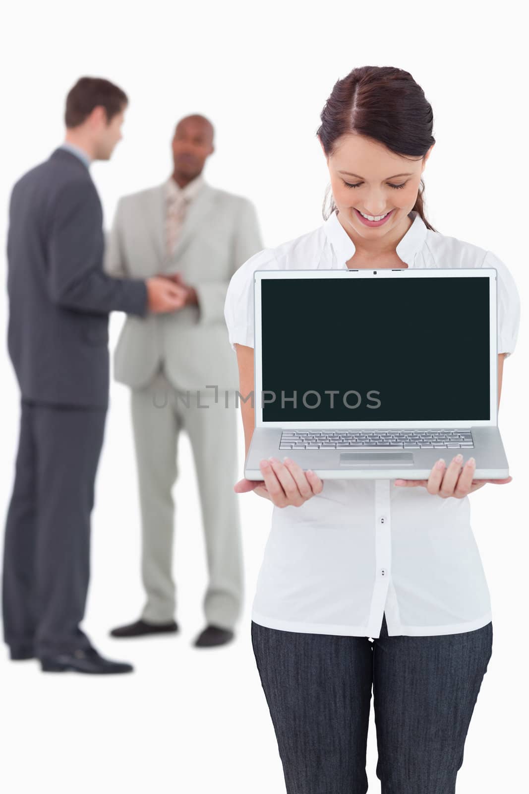 Businesswoman showing notebook with colleagues behind her against a white background