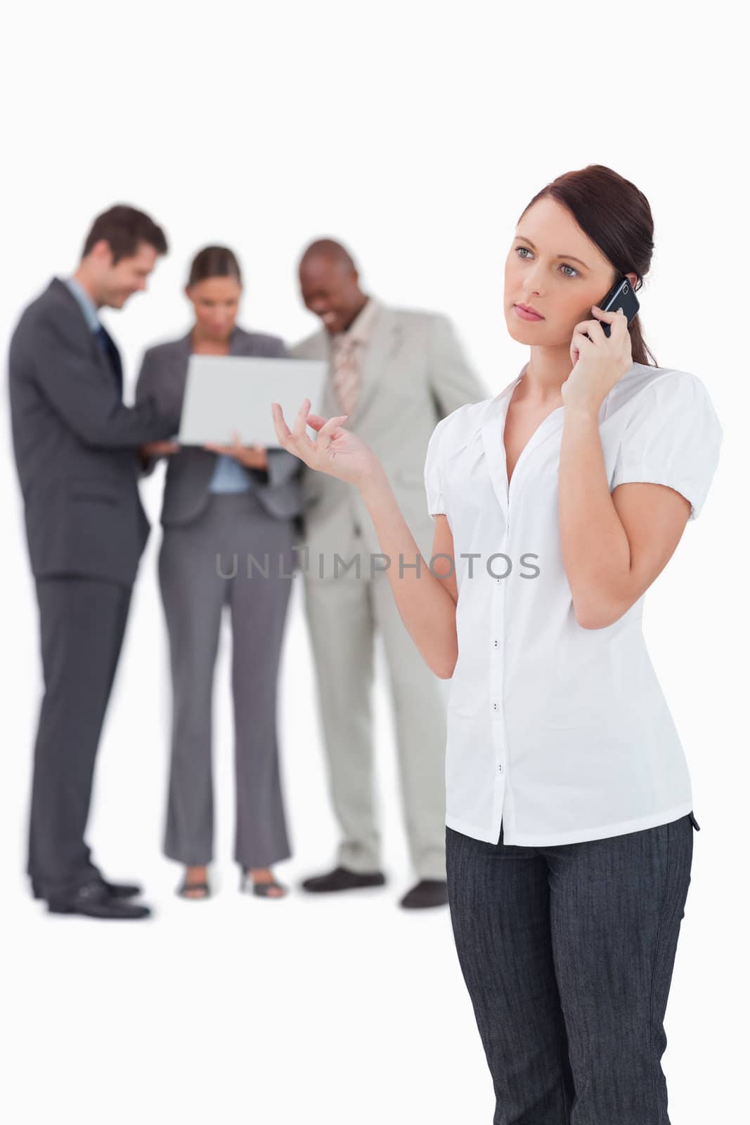 Businesswoman on the phone with colleagues behind her against a white background