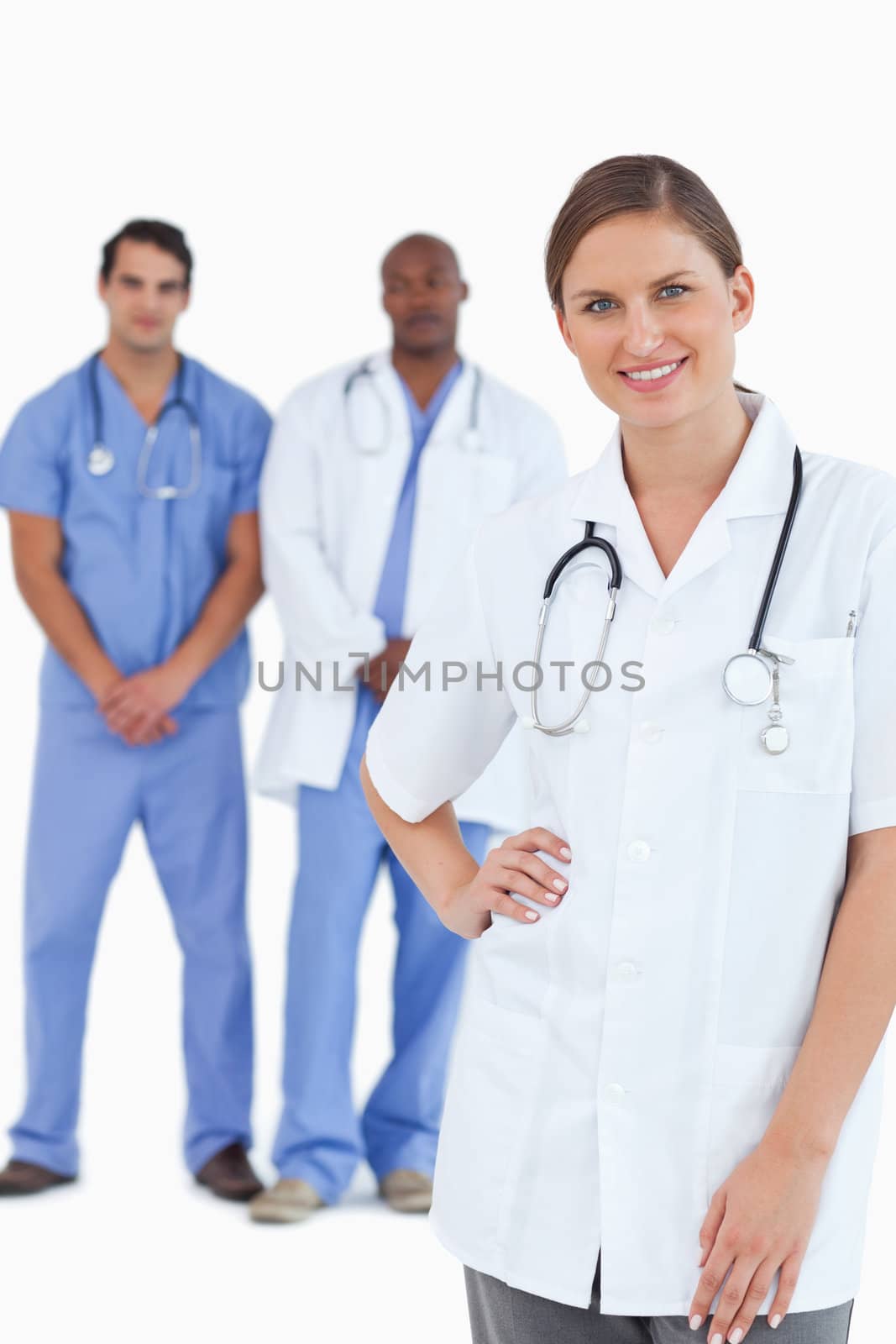 Smiling doctor with male colleagues behind her against a white background