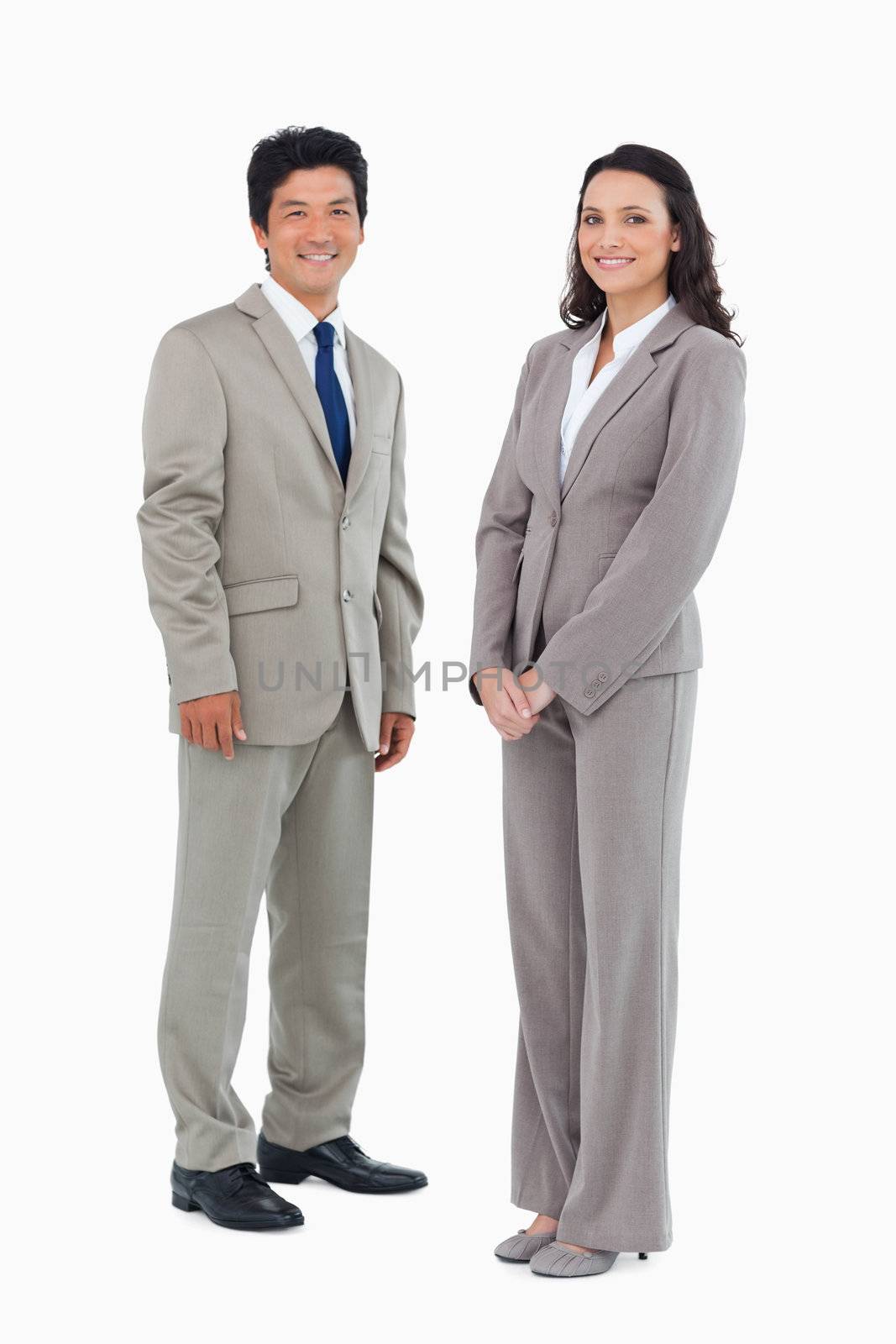 Smiling trading partners standing against a white background