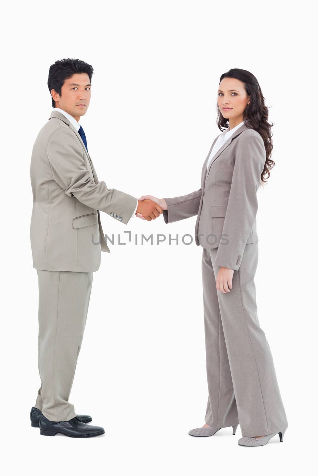 Side view of businesspeople shaking hands against a white background