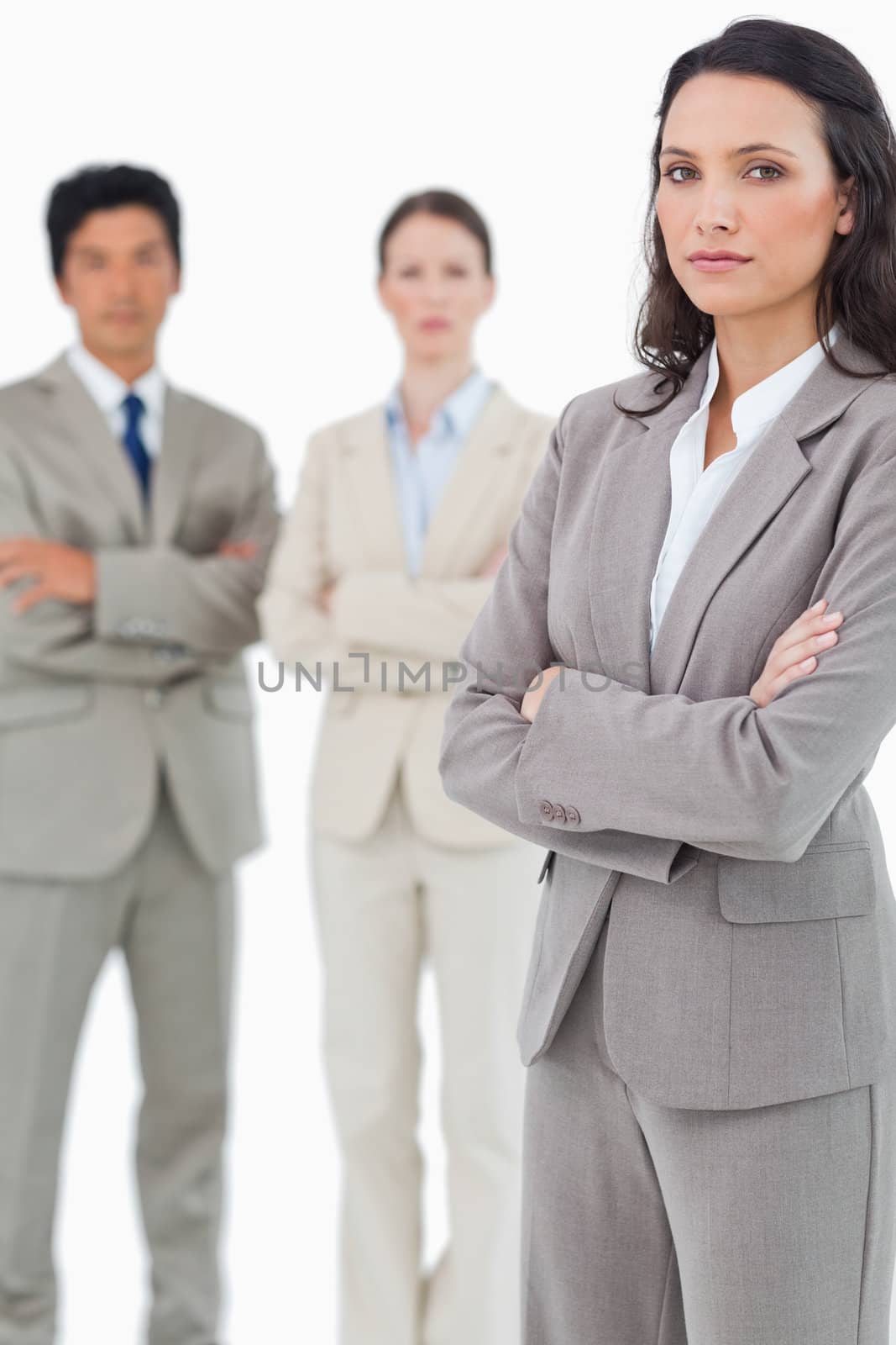 Tradeswoman with arms folded and colleagues behind her against a white background