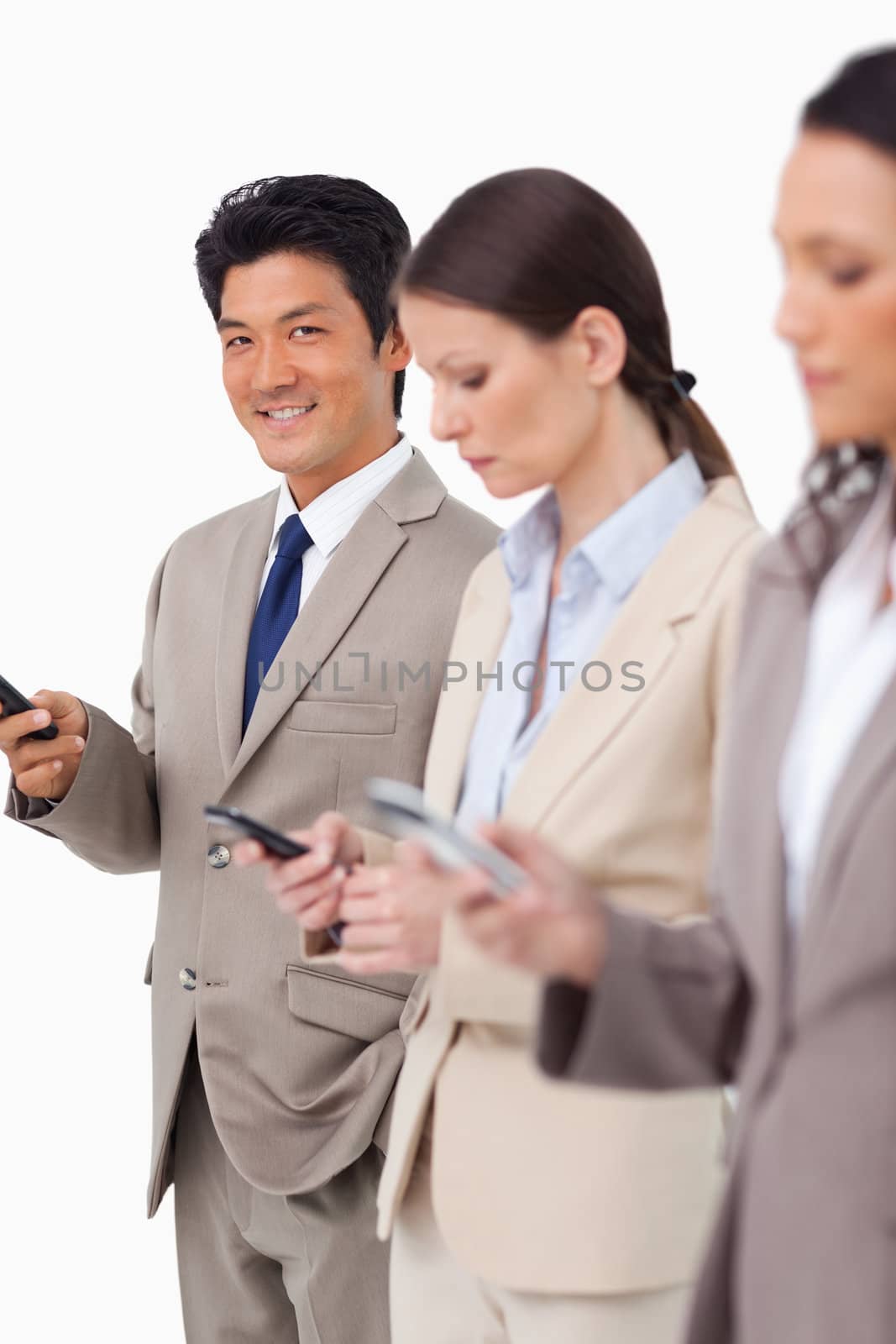 Smiling businessman with cellphone next to colleagues against a white background