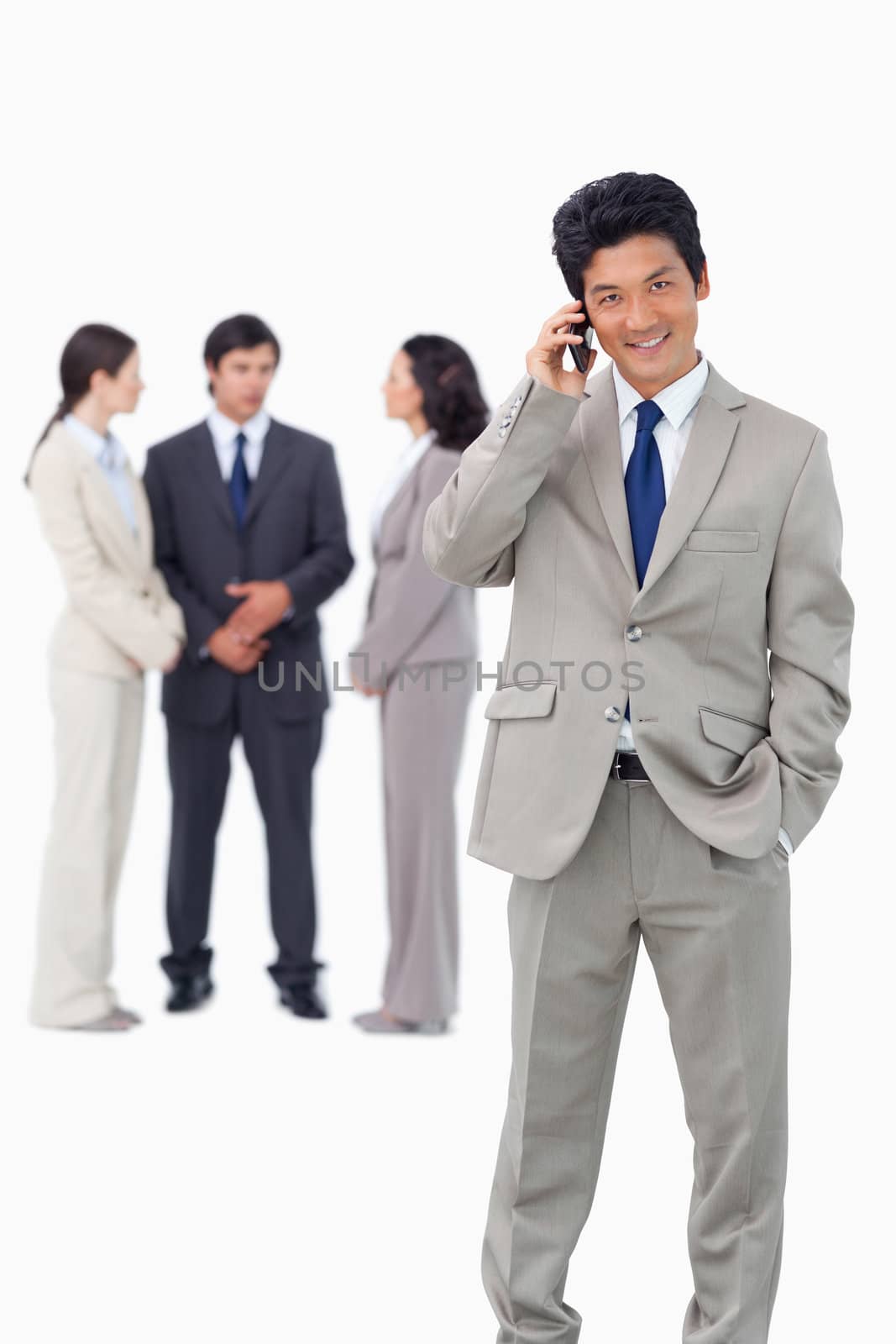 Businessman on cellphone with team behind him against a white background